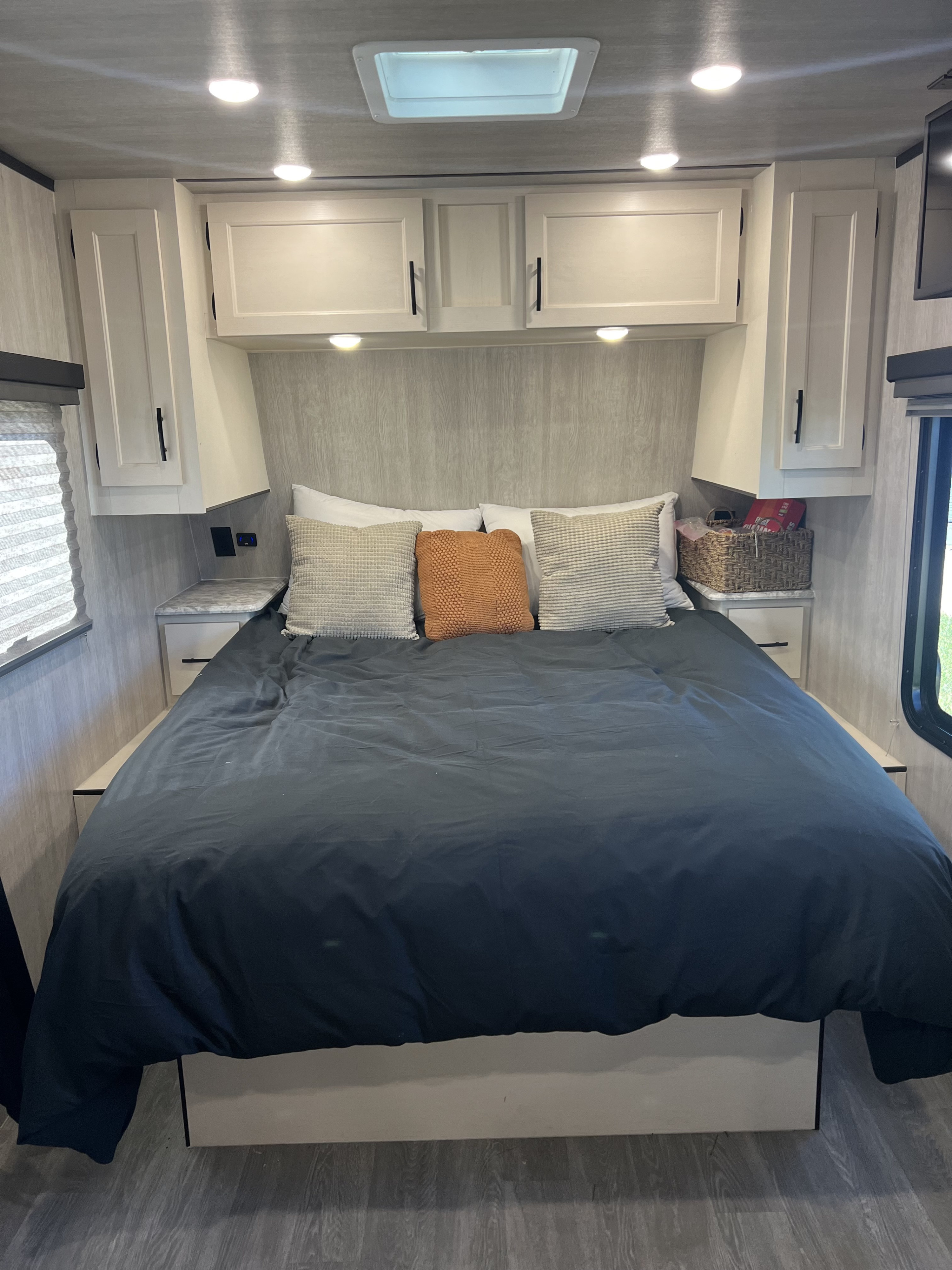 Modern RV rental bedroom: large bed, overhead cabinets, and built-in nightstands with lights, ensuring a comfortable stay.. Genesis Northland 2024