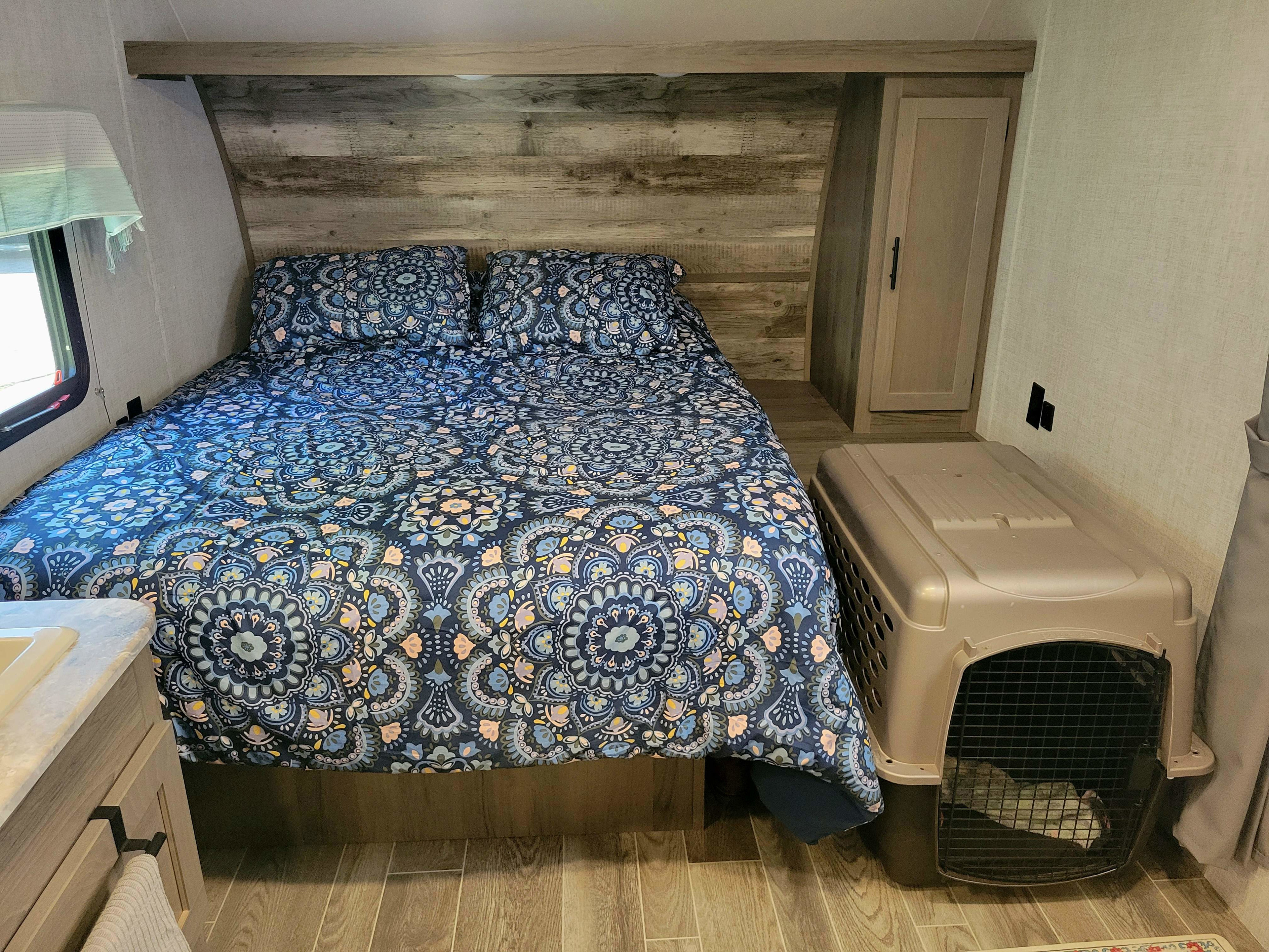 Pet-friendly RV rental interior: a cozy bed with blue patterned bedding and a dog crate.. Gulf Stream Ameri-Lite 2022