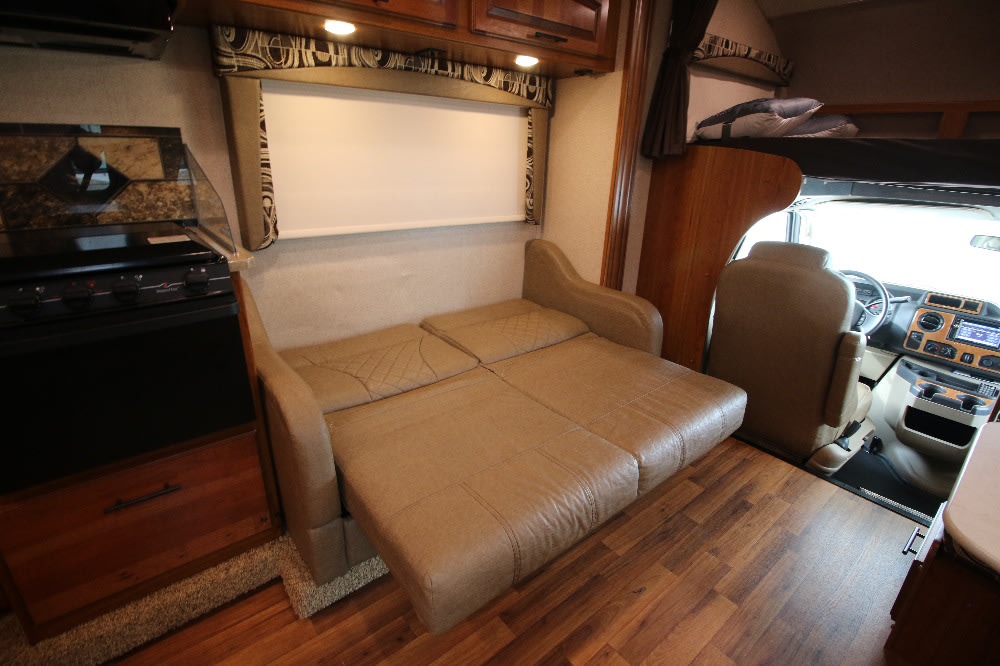 This RV rental interior offers a convertible sofa bed, compact kitchen, and overhead bunk above the cab area.. Jayco Greyhawk 2017