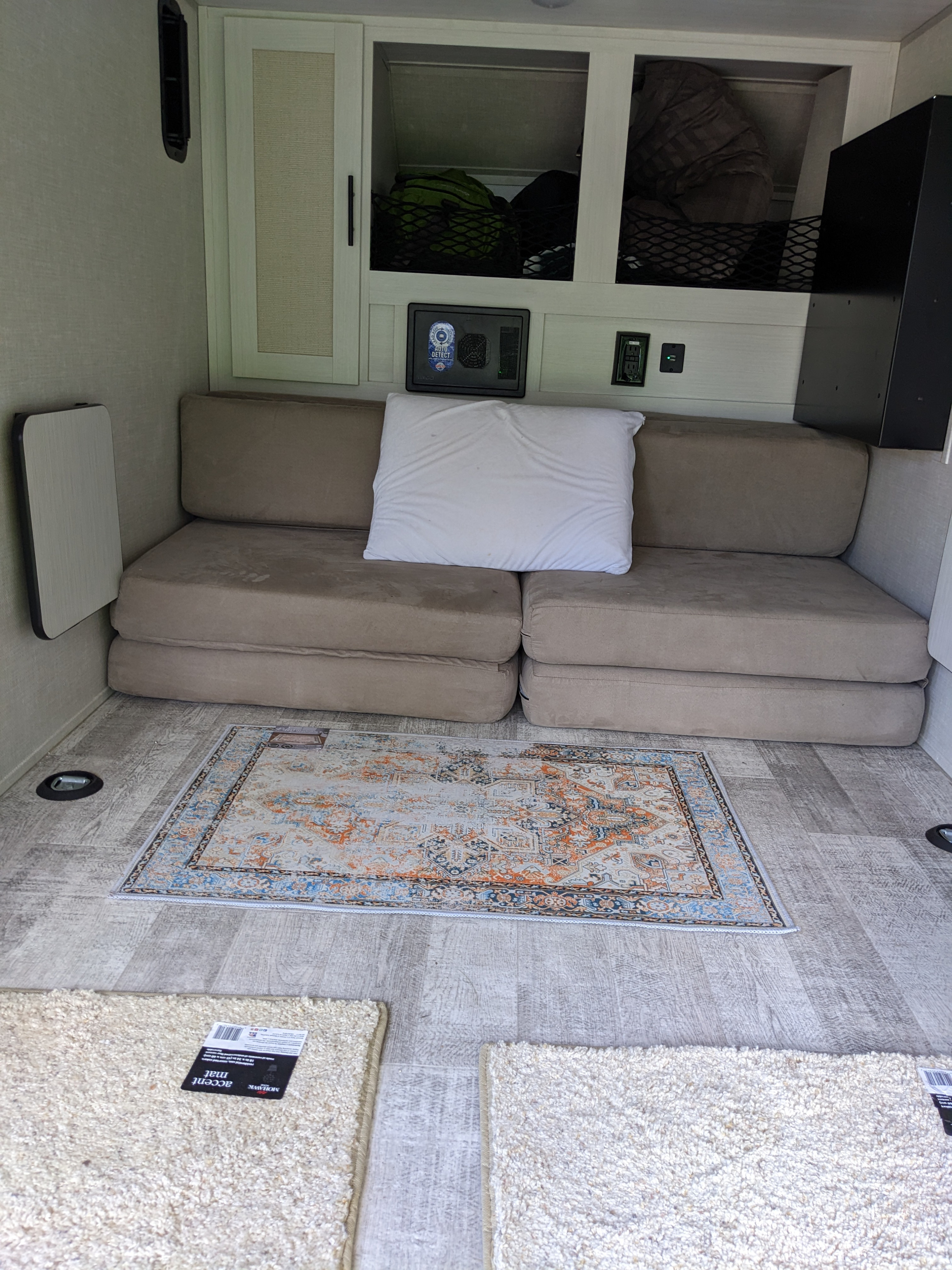 RV rental living space with a convertible sofa bed, overhead storage, and layered floor rugs.. Forest River 10.6 no boundaries 2022