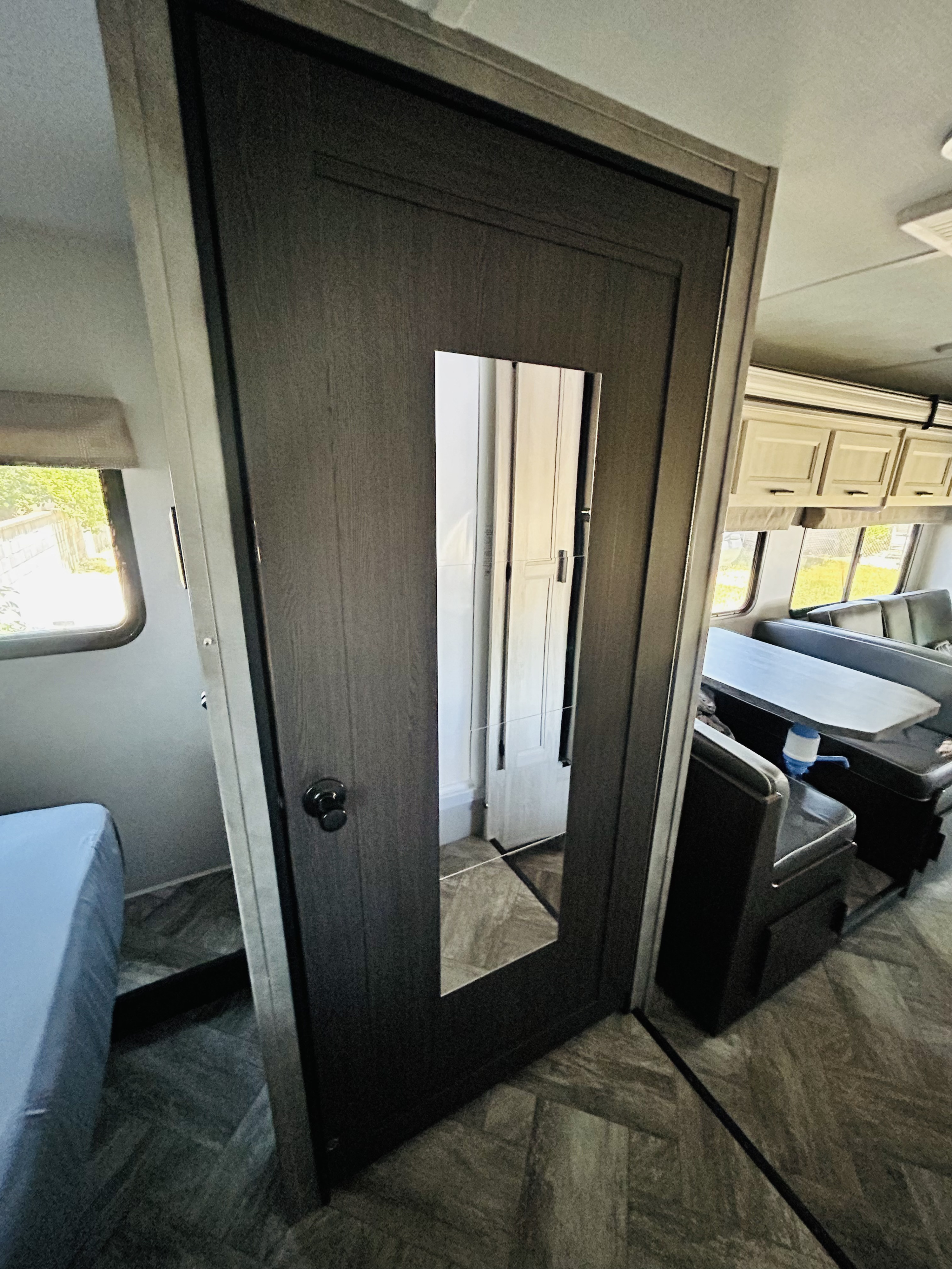 RV rental interior: View of a bedroom (left) and dinette (right) separated by a door; features wood-pattern floor.. Forest River Sunseeker LE 2022