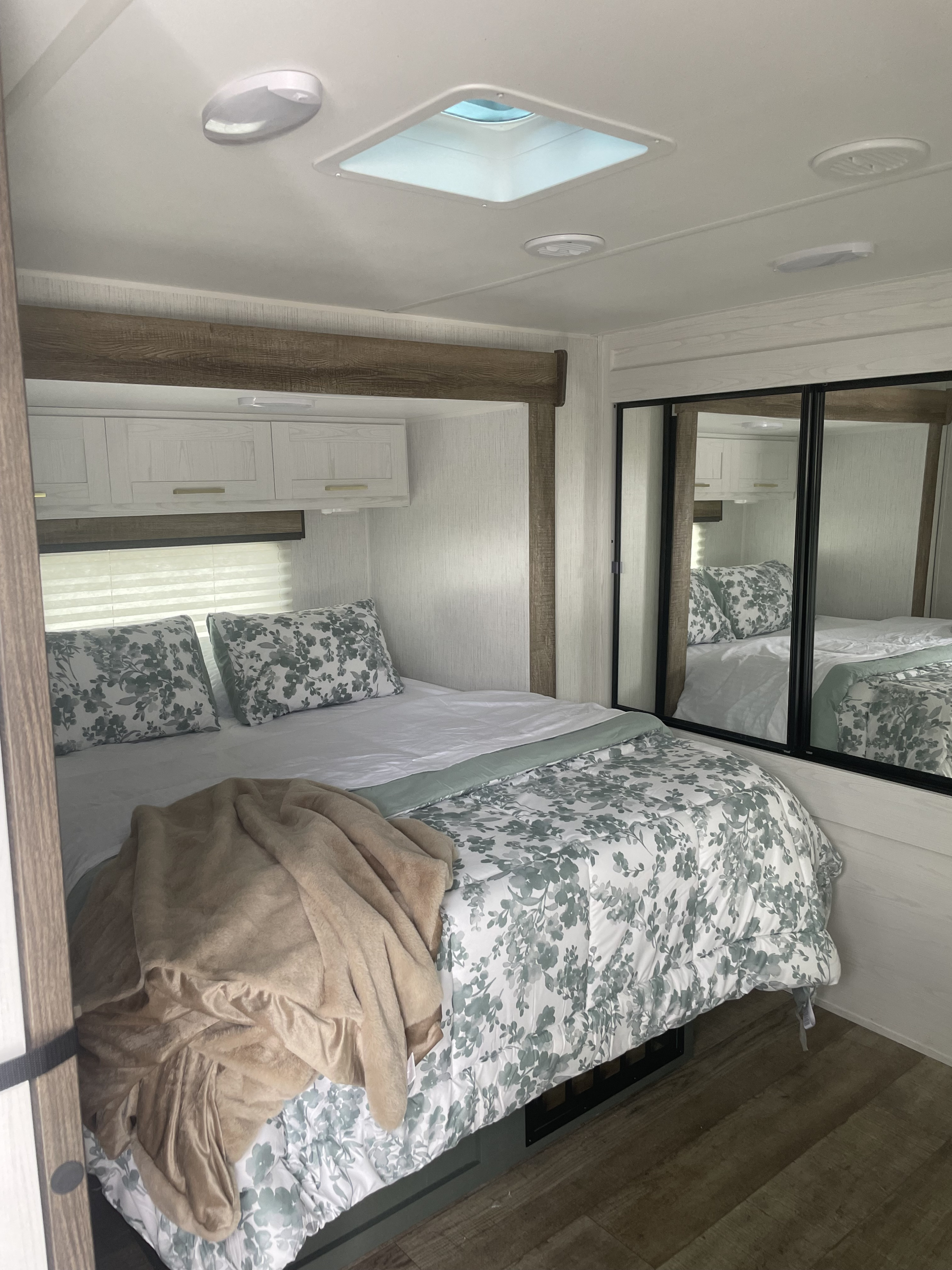 Cozy RV rental bedroom: features floral bedding, overhead lights, a skylight, and mirrored closets.. Keystone RV Eddie Bauer 34bsbh 2024