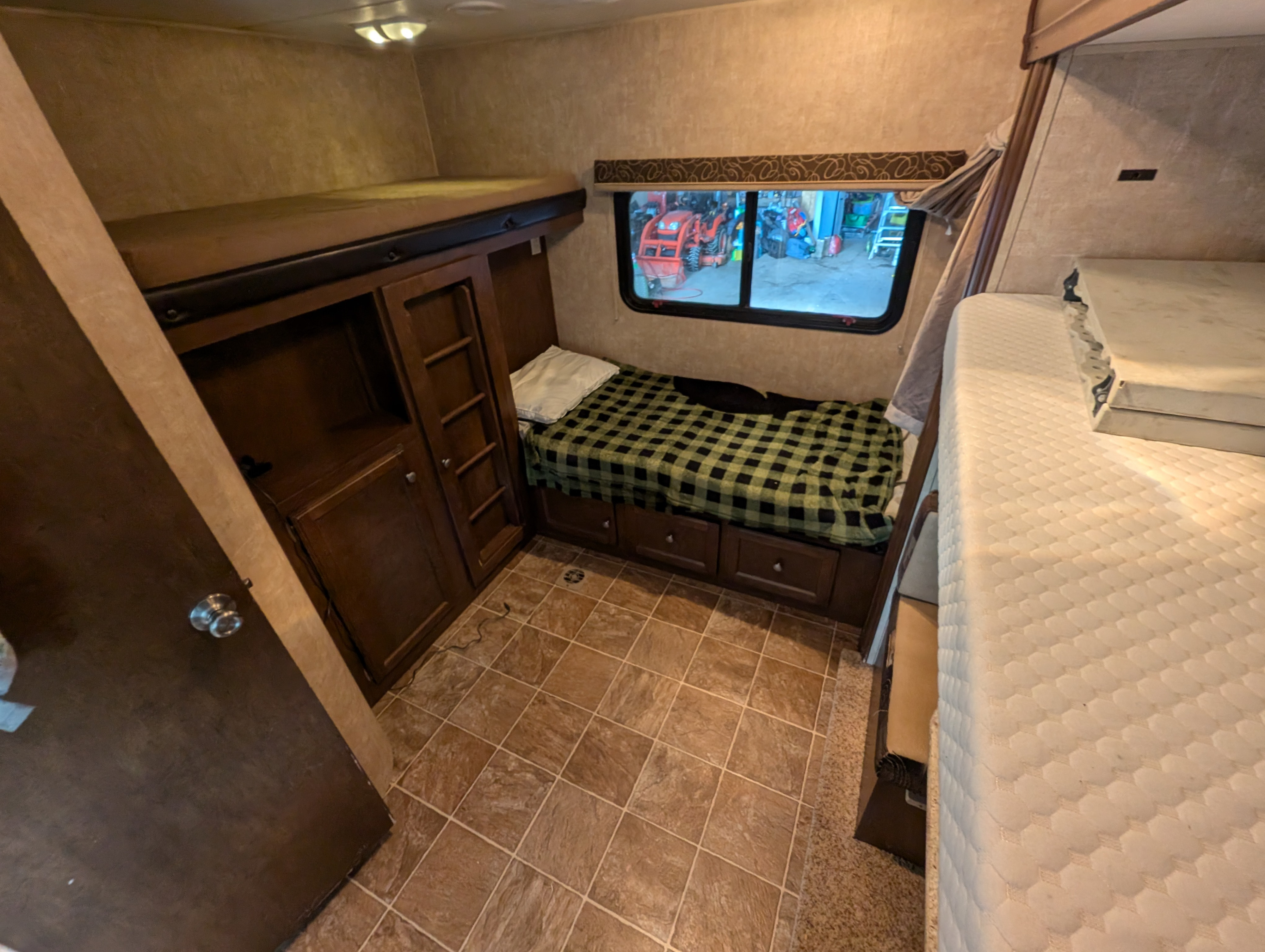 RV rental interior with bunk beds, storage cabinetry, and a window view, offering comfortable sleeping arrangements.. Sport Trek Sport Trek Trailer 2014
