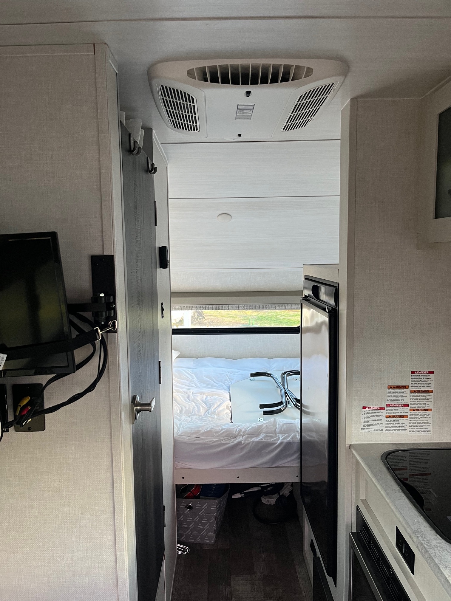 Explore the cozy RV rental interior: bedroom with window, kitchen area with fridge & stovetop, plus TV & AC.. Forest River R-Pod 171 2022