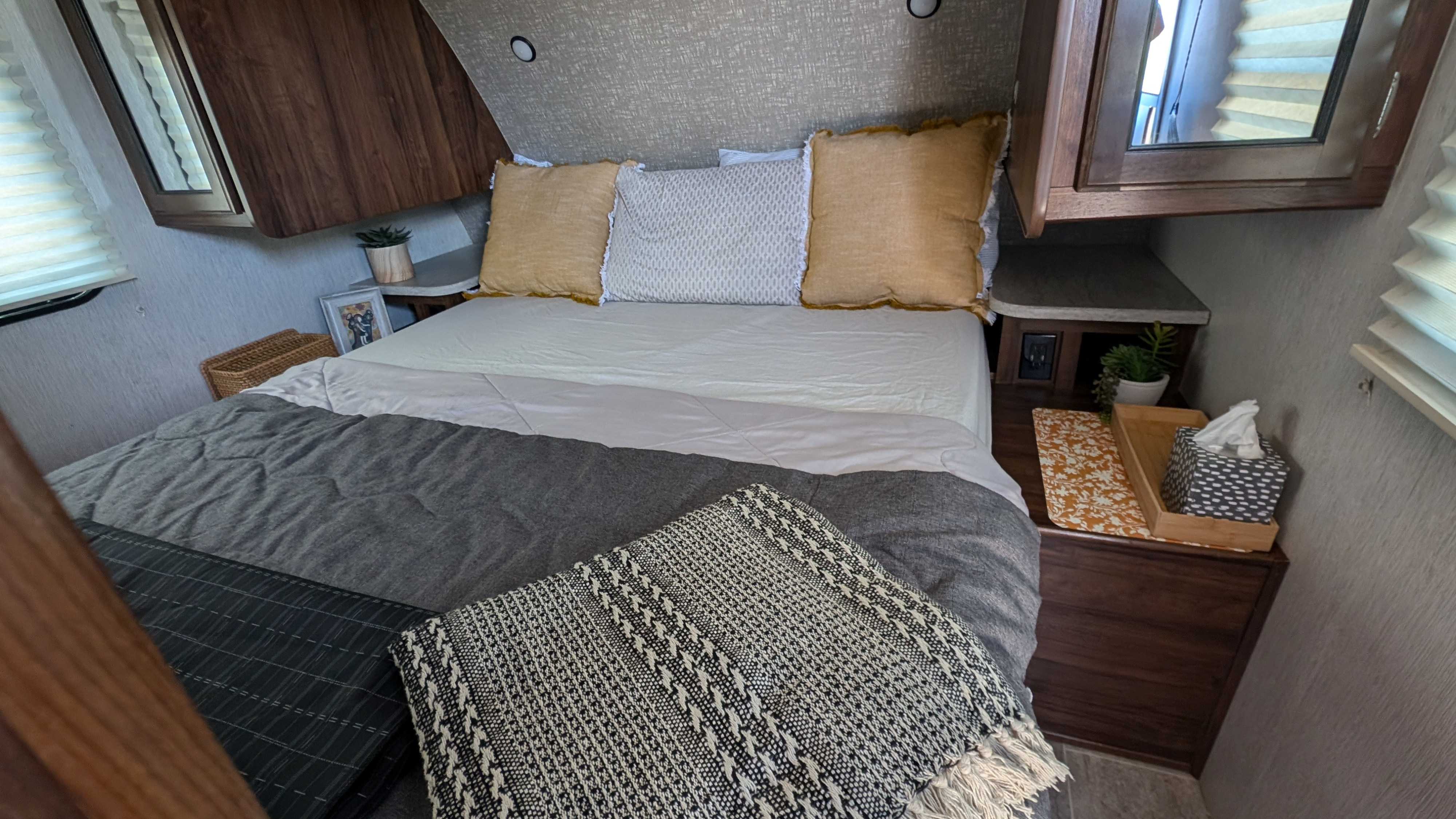 Cozy RV rental bedroom featuring a well-appointed bed with textured blankets, bedside tables, and storage cabinets.. Heartland RVs Mallard 2019