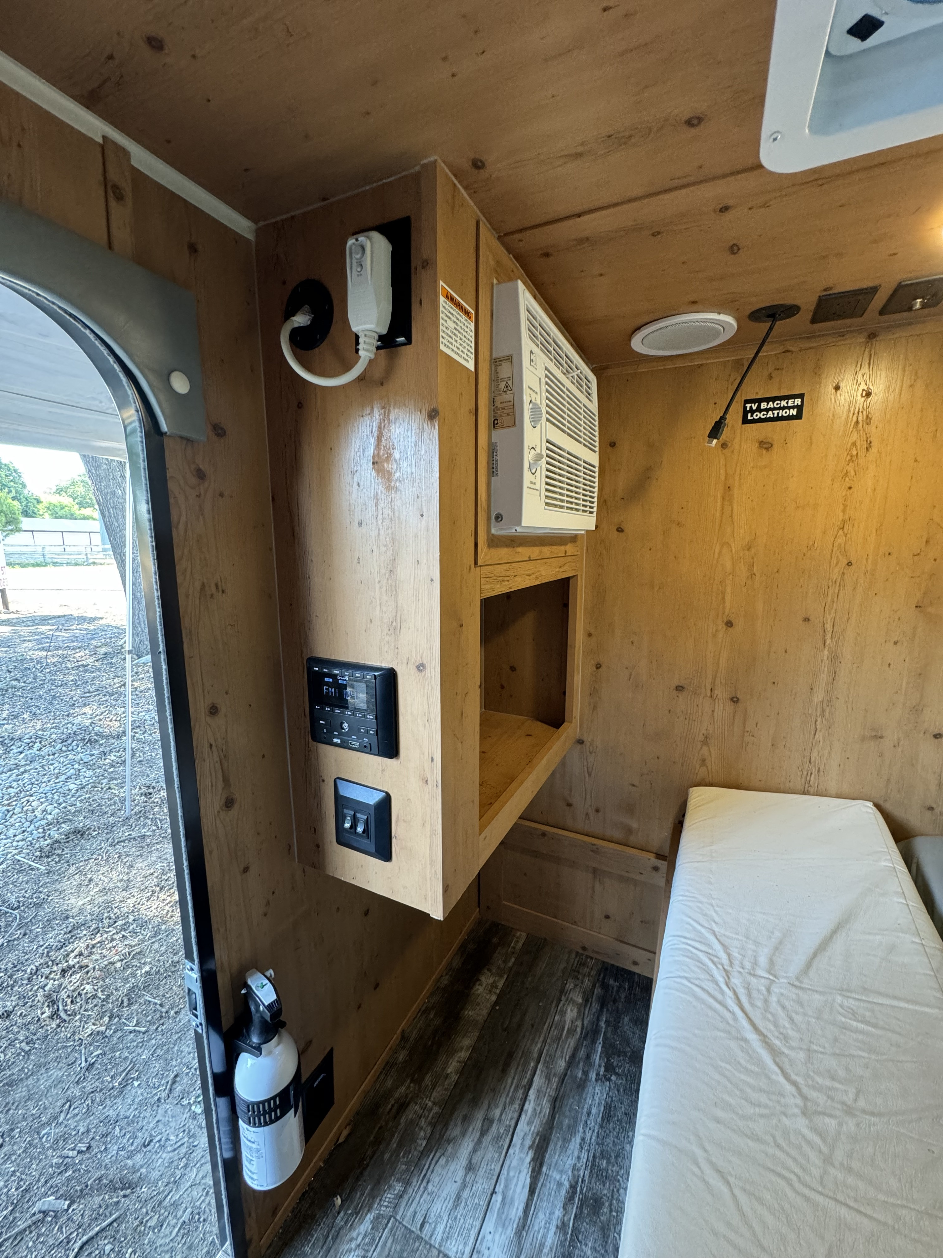 Compact rv rental interior featuring wood paneling, AC unit, stereo, and sleeping area. Ready for your next adventure.. Sunset Park RV SunRay 2022