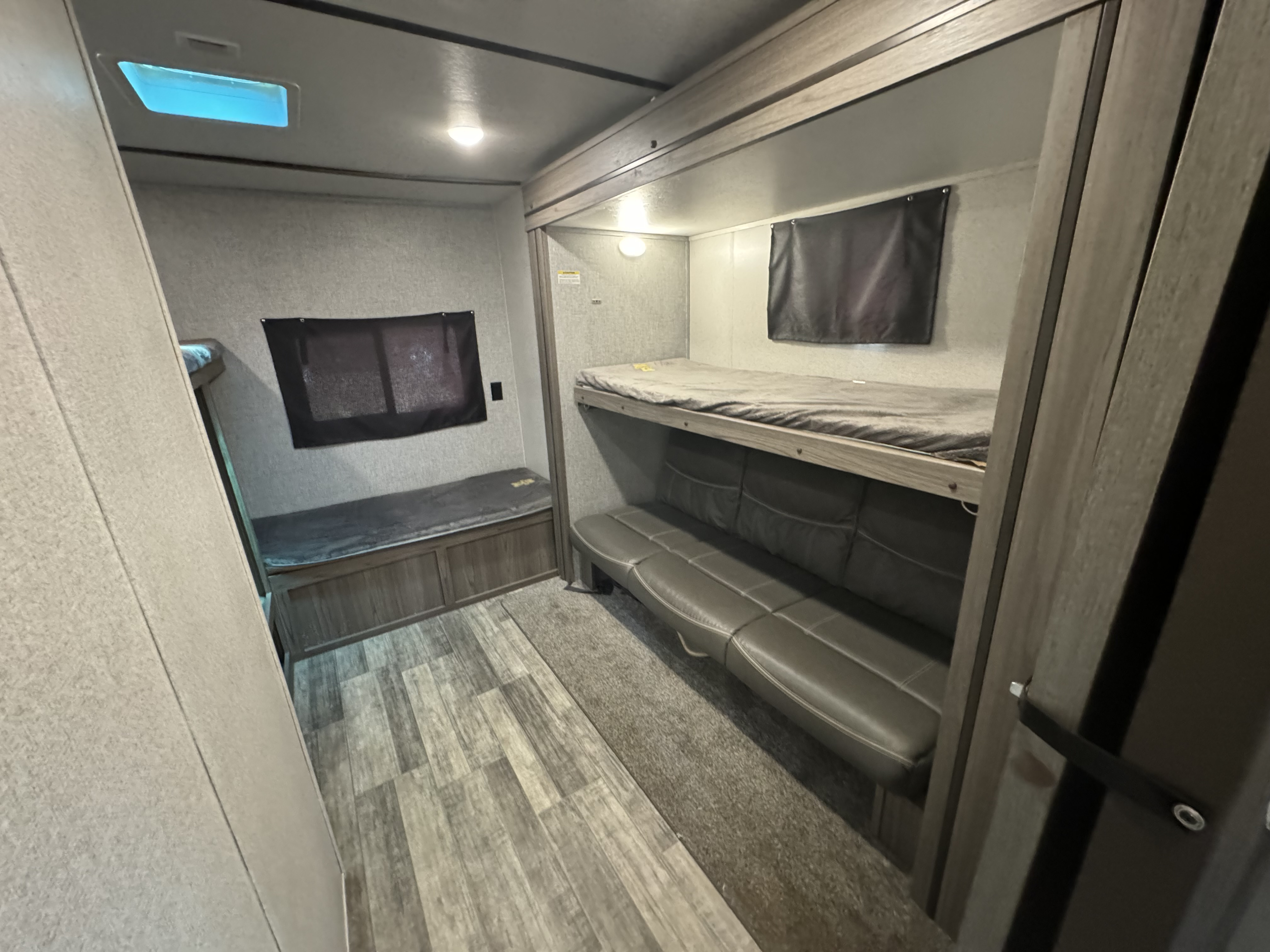 RV rental bunk room featuring a top bunk, convertible sofa/bed, and storage bench, providing comfortable sleeping options.. Crossroads RV Volante 2020