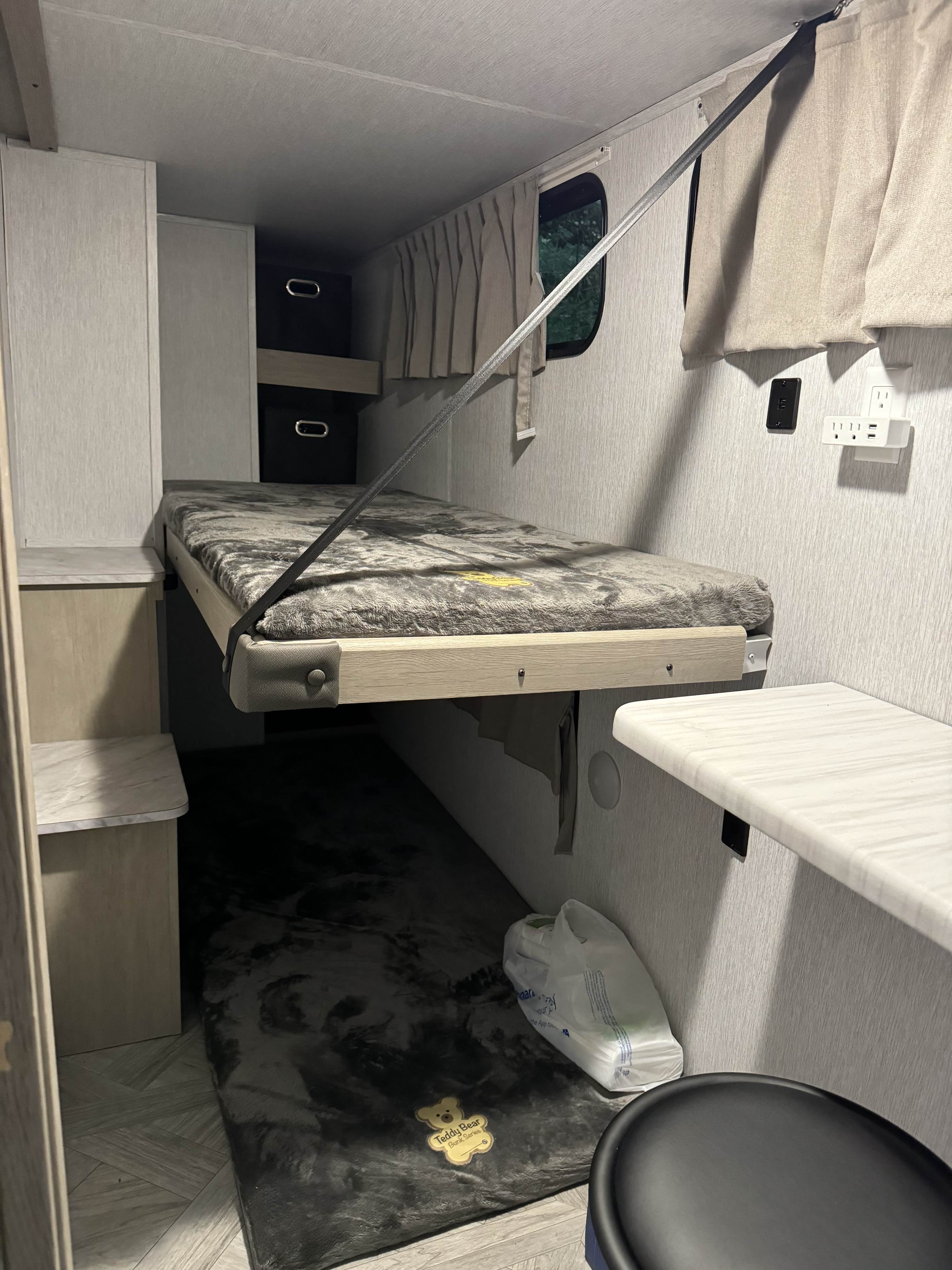 Cozy RV rental interior with a lowered bunk bed, secured by a strap. Perfect for family camping and travel adventures.. Forest River Wildwood Platinum 2024