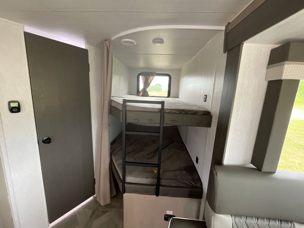 RV rental interior: cozy bunk beds with ladder, a door, & window in a compact camper.. Forest River Salem Cruise Lite Platinum 2024