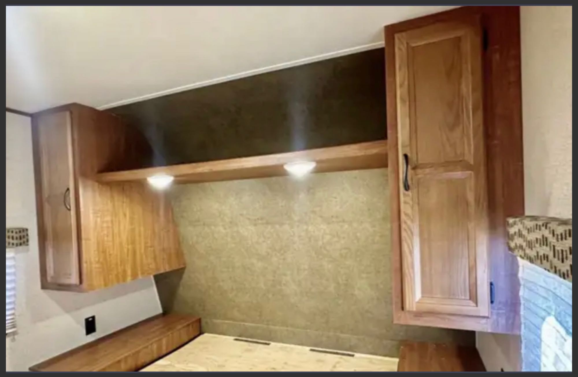 RV rental bedroom interior: bed base, overhead shelf with lights, and wooden storage cabinets. Compact and functional space.. Jayco Jay Flight 2015