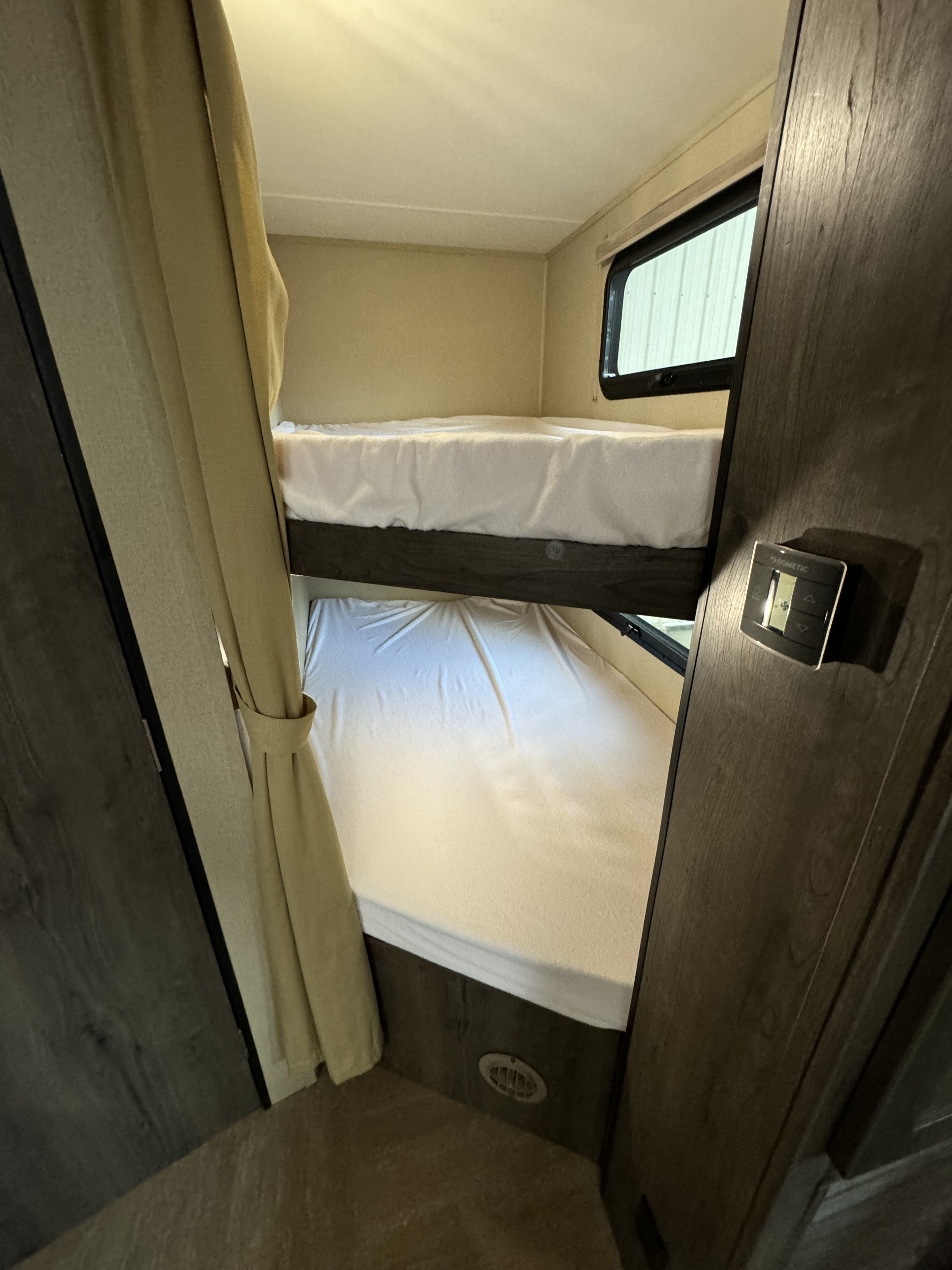 Inside an rv rental: functional bunk beds with windows, curtains, and climate controls for comfortable travel.. Dutchmen Kodiak 2015