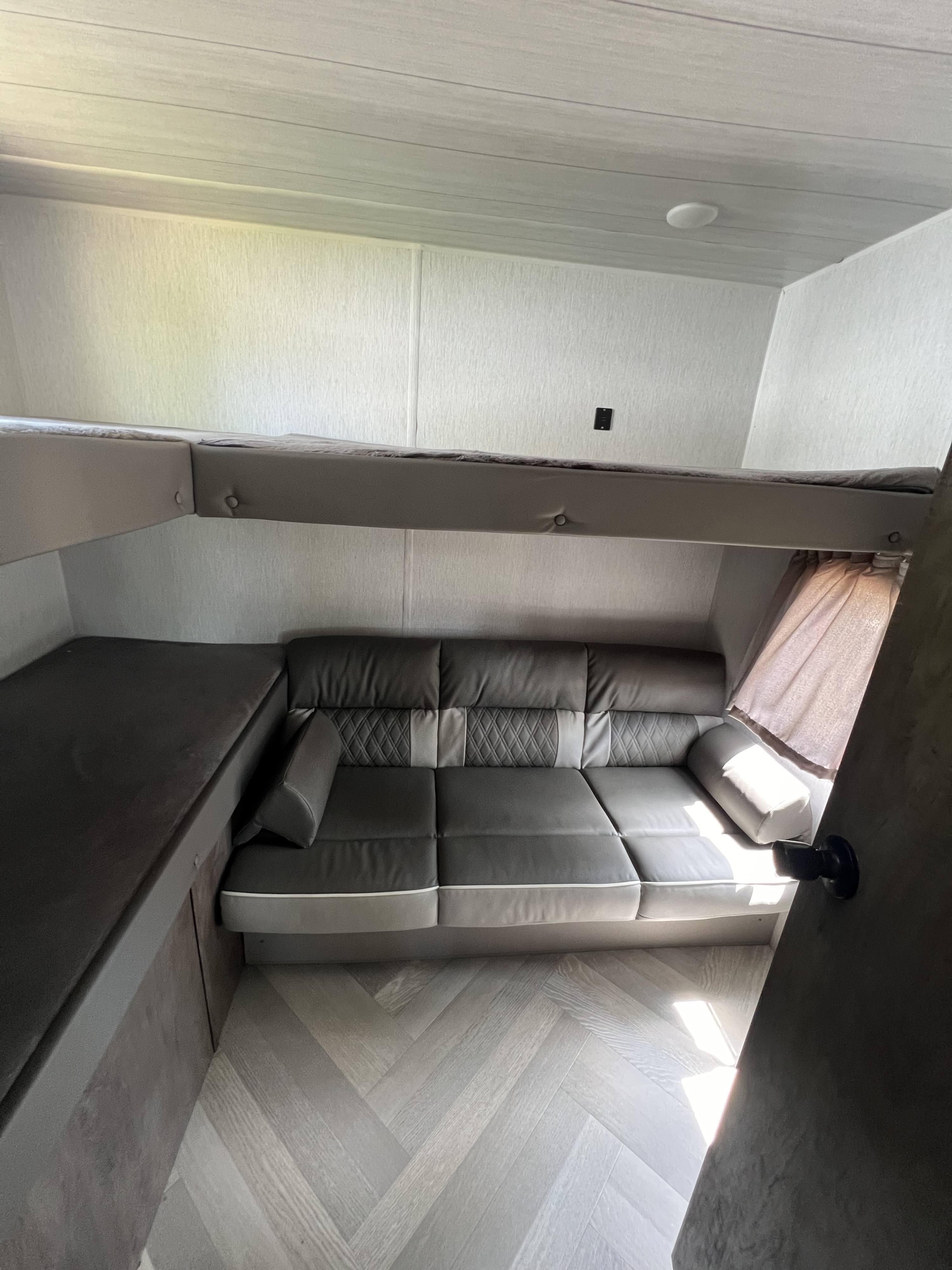 RV rental: Dark grey convertible sofa, upper bunk, and lower bunk/bench. Light walls, herringbone floor.. Forest River Salem Cruise Lite 2022