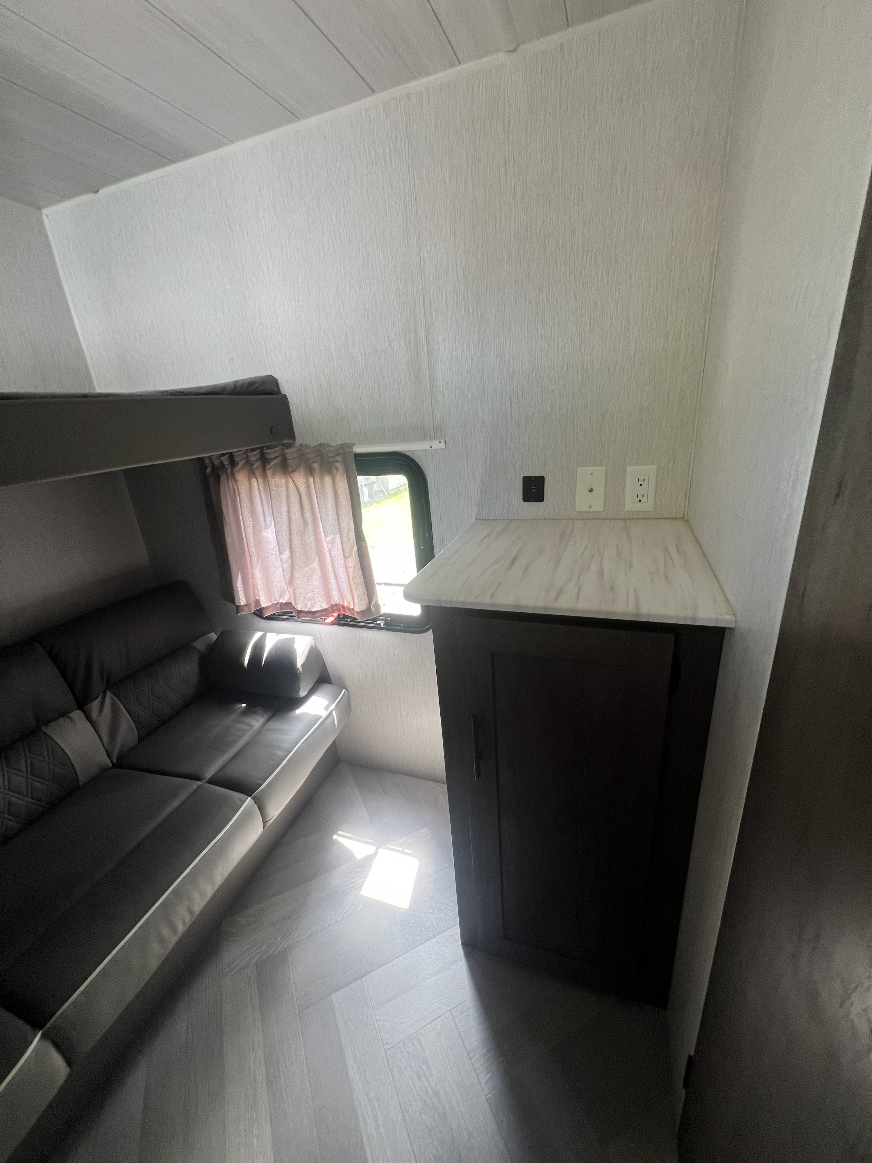RV rental interior: Bunk bed, sofa, a small counter with outlets, and light wood herringbone flooring.. Forest River Salem Cruise Lite 2022