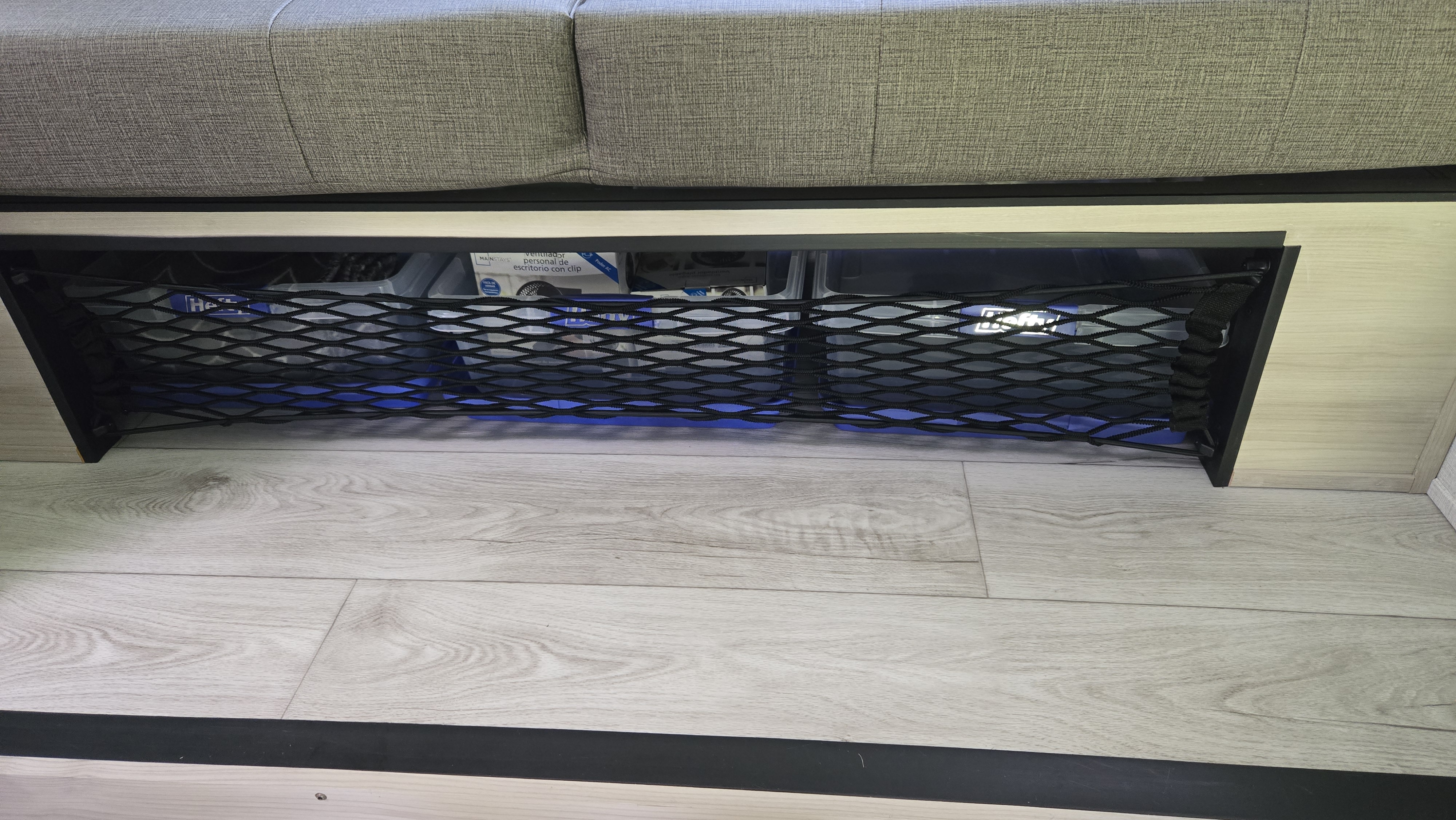 Under-seat mesh storage with blue light in an RV rental. Perfect for keeping travel essentials organized.. East to West Silver Lake 2024