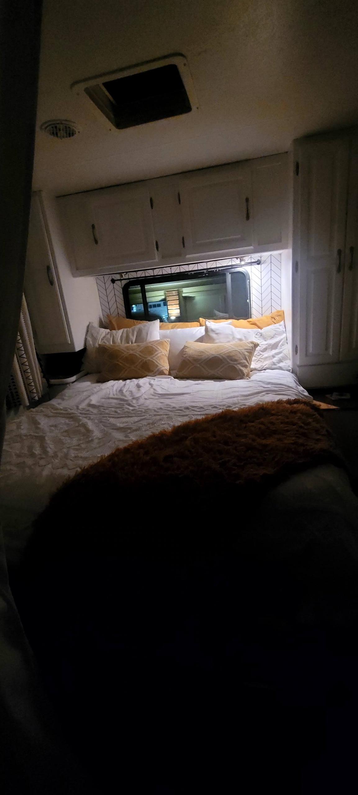 Cozy RV rental bedroom with white and yellow bedding, overhead cabinets, and a night view from the window.. Coachmen Freelander Premier 2006