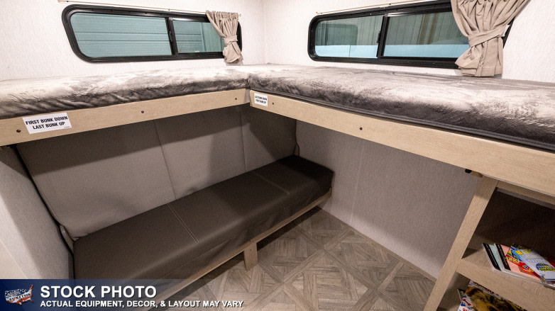 Efficient RV rental interior with L-shaped bunk beds and versatile lower seating/storage, optimizing space for travelers.. Forest River Wildwood Platinum 2024