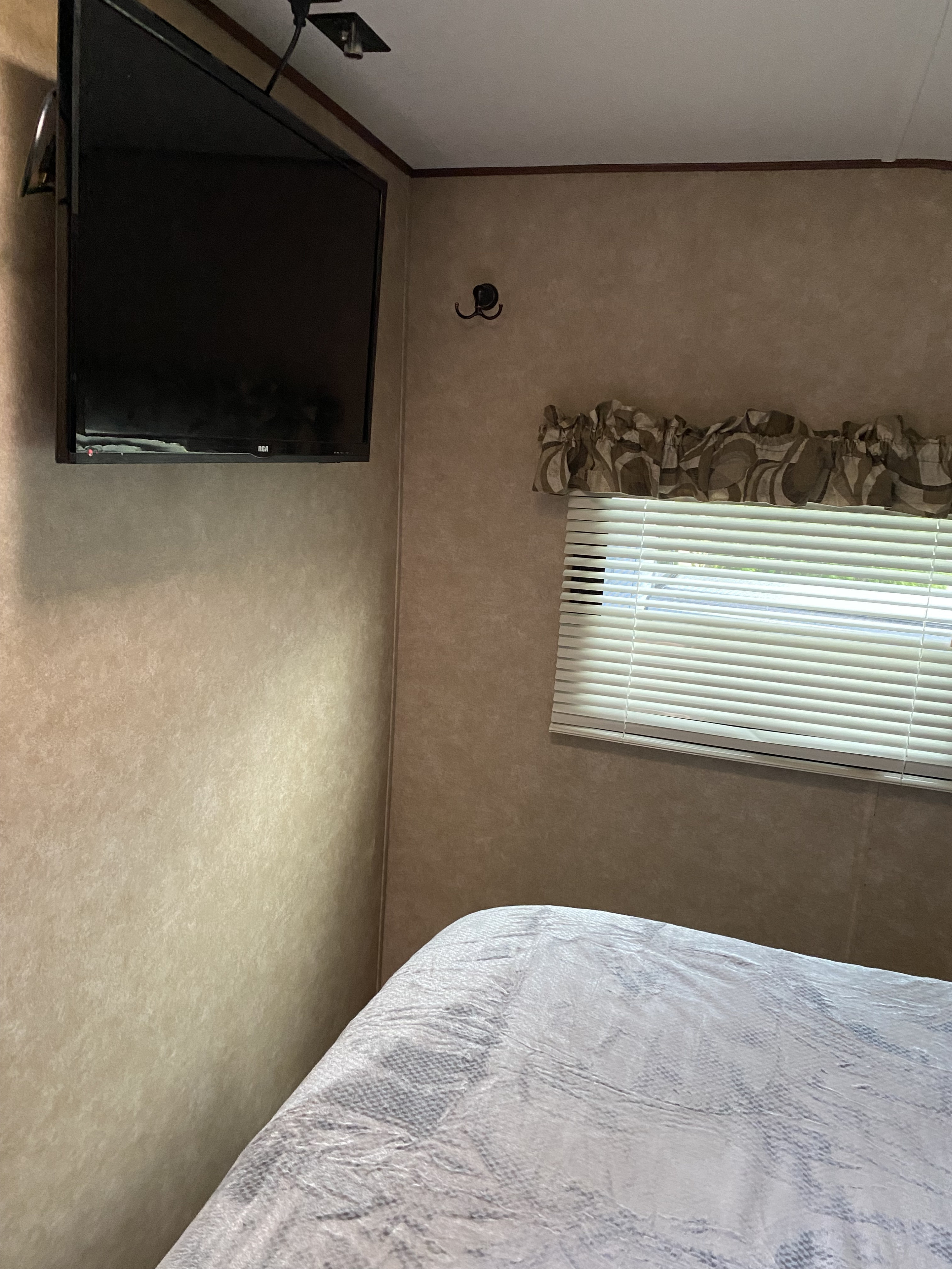 Cozy RV rental bedroom features a wall-mounted TV, window with blinds, and bed, optimizing compact space.. Crossroads RV Z-1 2013