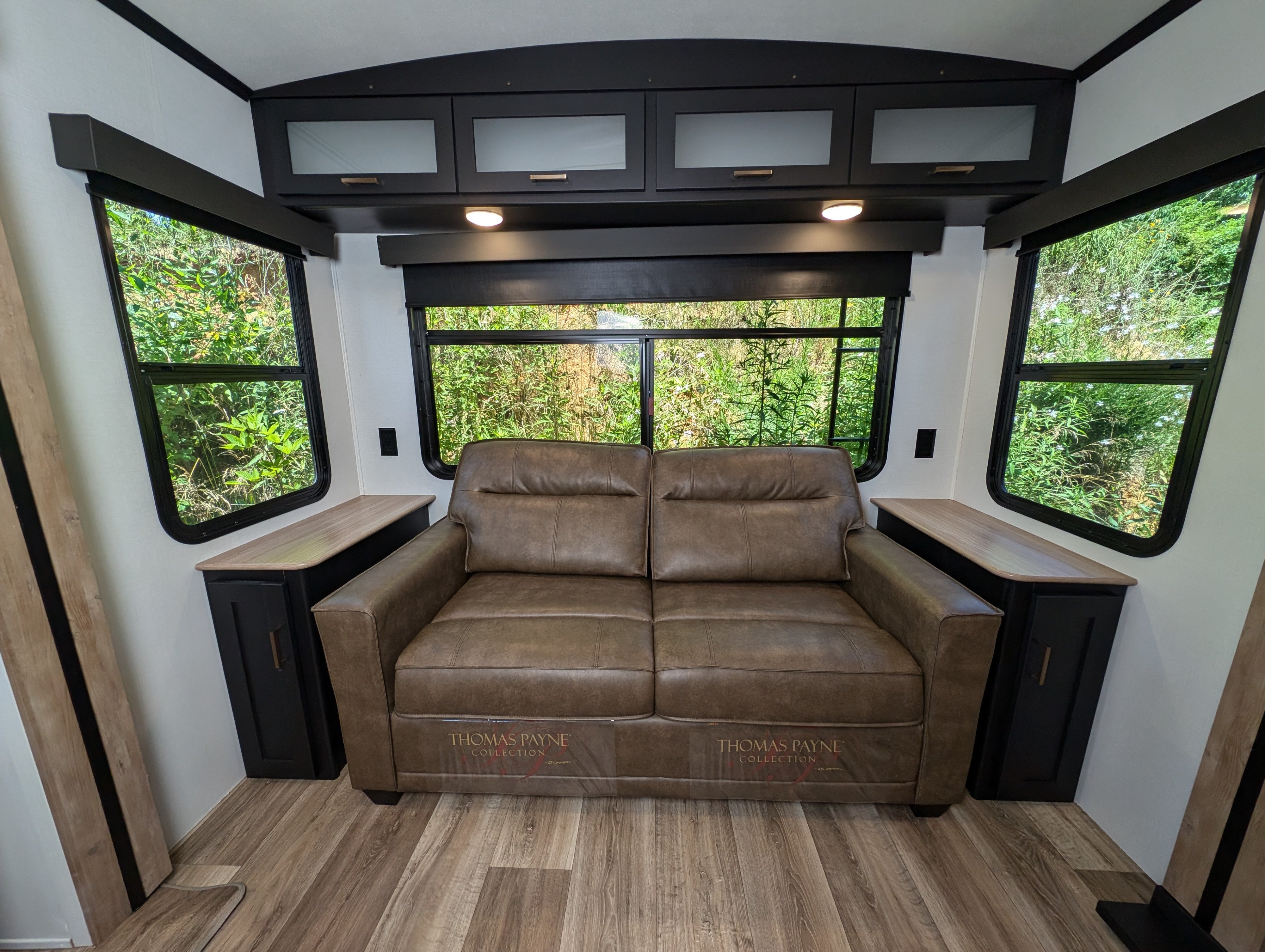RV rental: Comfortable RV living space featuring a brown leather sofa, large windows, and overhead storage cabinets.. Keystone Outback 2023