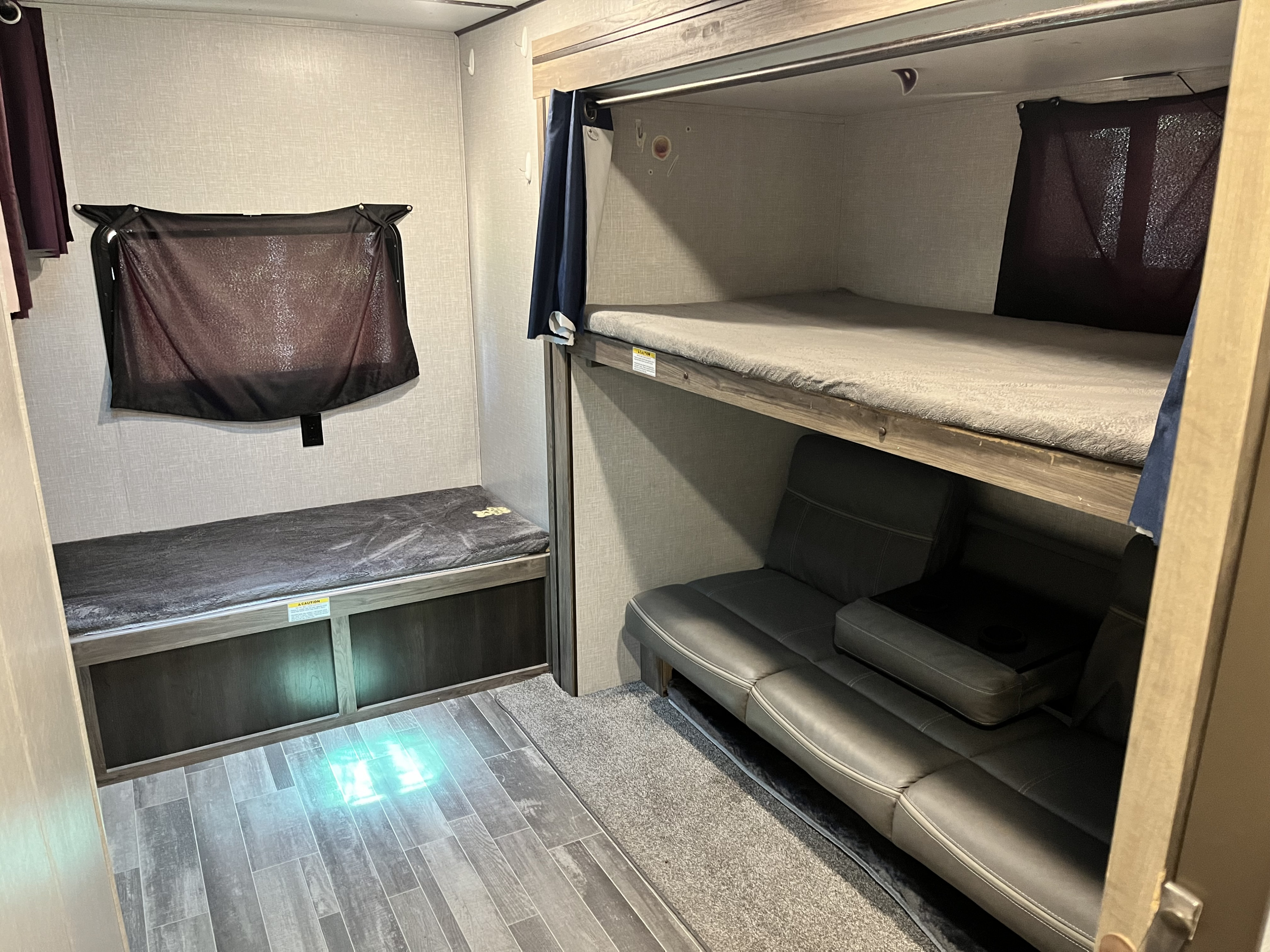 Cozy RV rental bunkhouse area showcasing a side bed, double bunk beds, and a sofa for extra sleeping space.. Crossroads RV Zinger 2022