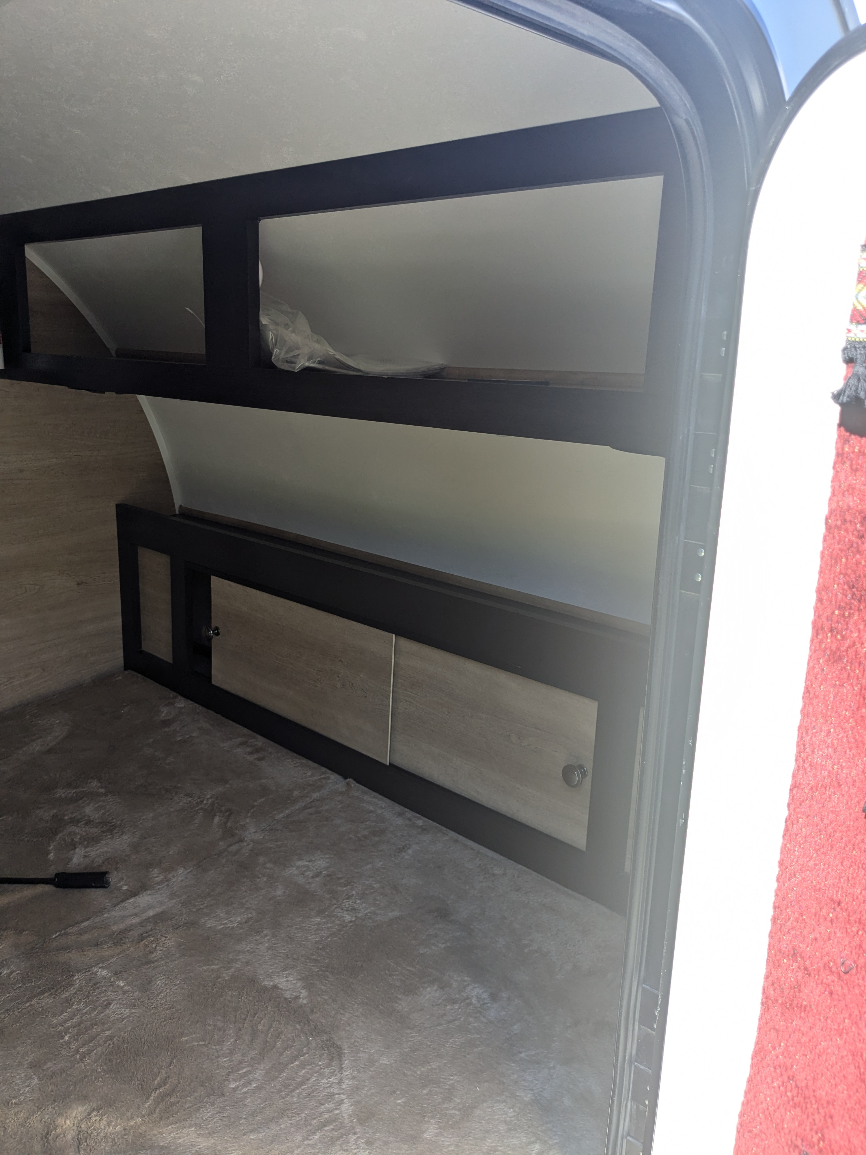 RV rental interior showing compact storage with open shelves, wood-look cabinets, and a textured floor.. Braxton Creek Bushwhacker 2021