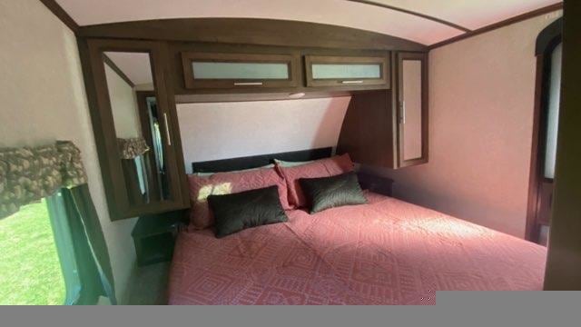 Cozy RV rental bedroom with a comfy bed, overhead storage, and a window. Perfect for your next travel adventure.. Keystone RV Cougar 2020