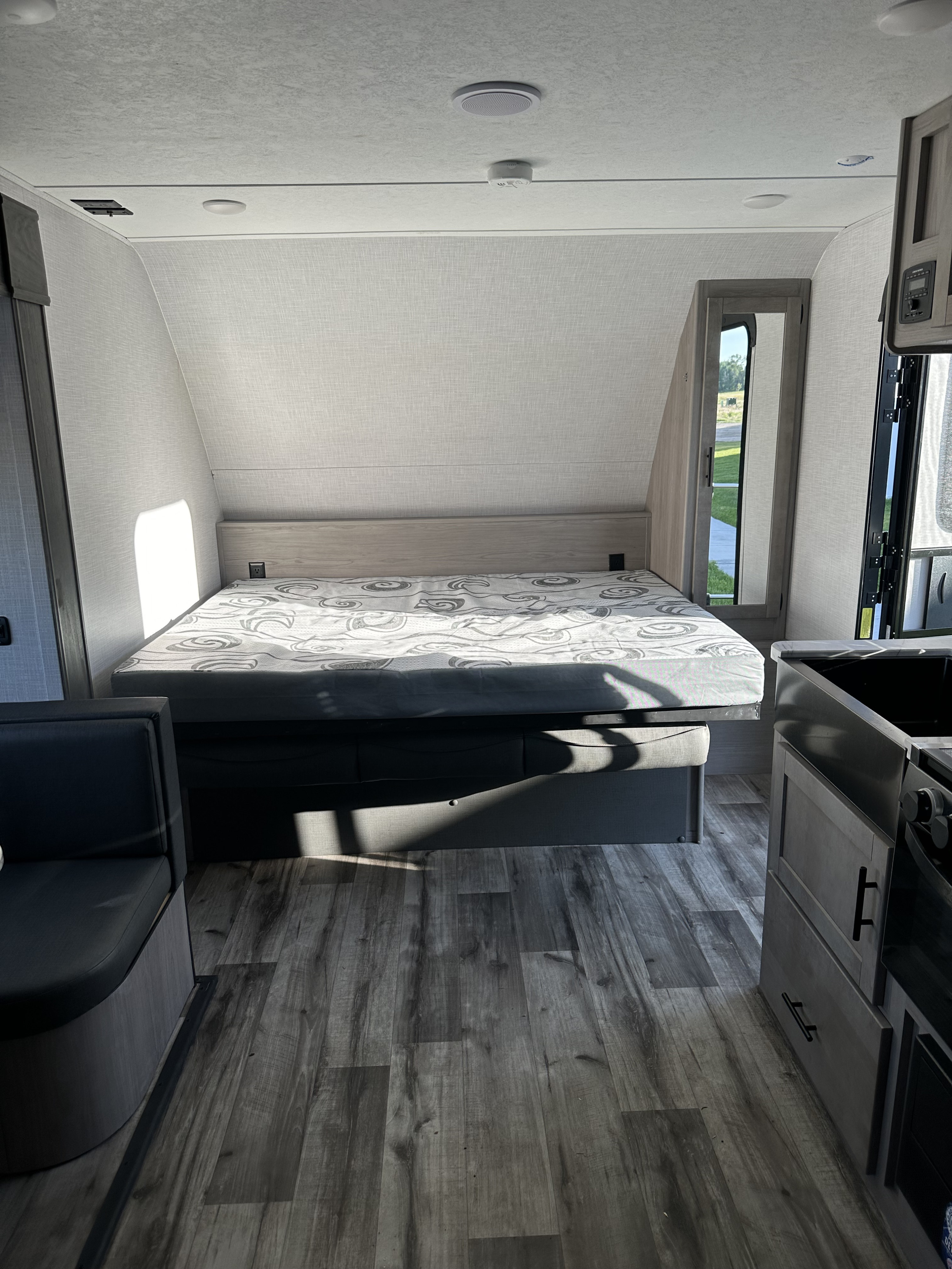 RV rental interior: bedroom with bed, seating, and kitchen. Bright, modern space for comfortable travel.. Dutchmen Coleman Light 2022