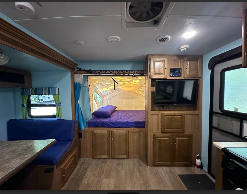 RV rental interior featuring a cozy dinette, pop-out bed, and entertainment system. Ideal for travel comfort.. Forest River Rockwood Roo 2019