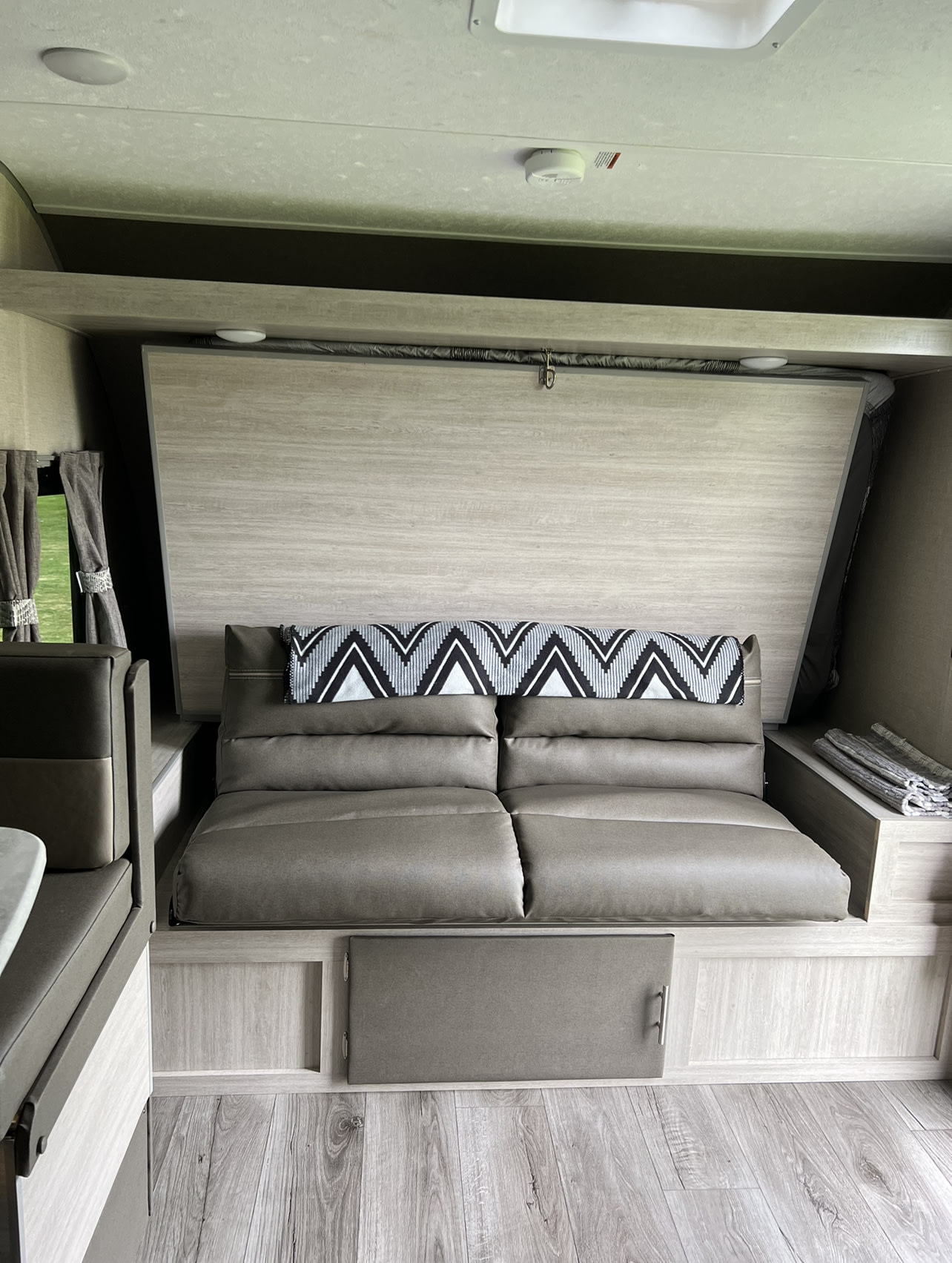 Cozy RV rental interior features a convertible sofa bed with modern gray cushions and wood-look finishes.. Forest River Aurora Aurora 2022