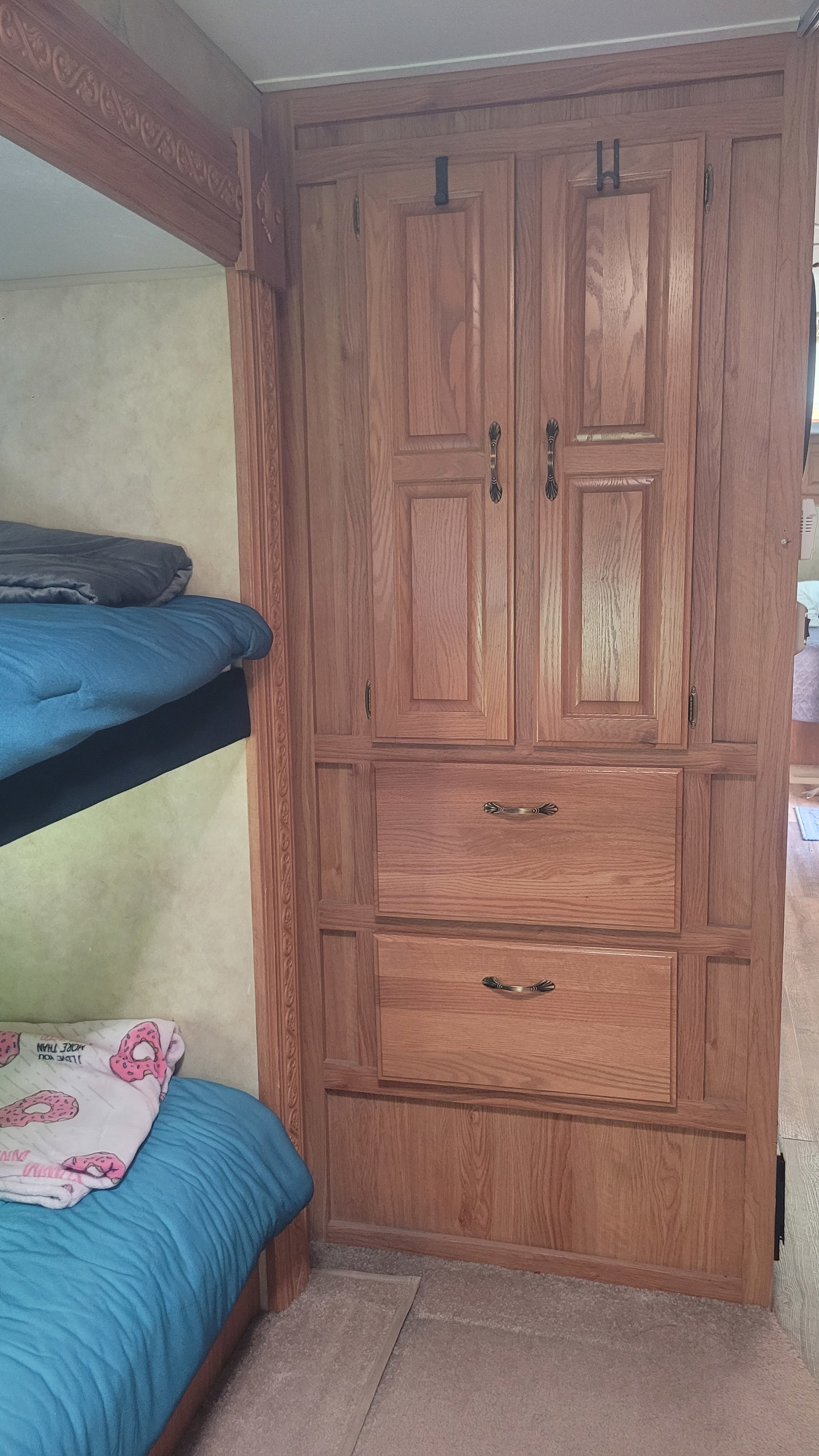 Cozy RV rental interior showcasing a large wooden wardrobe with drawers, next to built-in bunk beds.. Jayco Eagle 2006