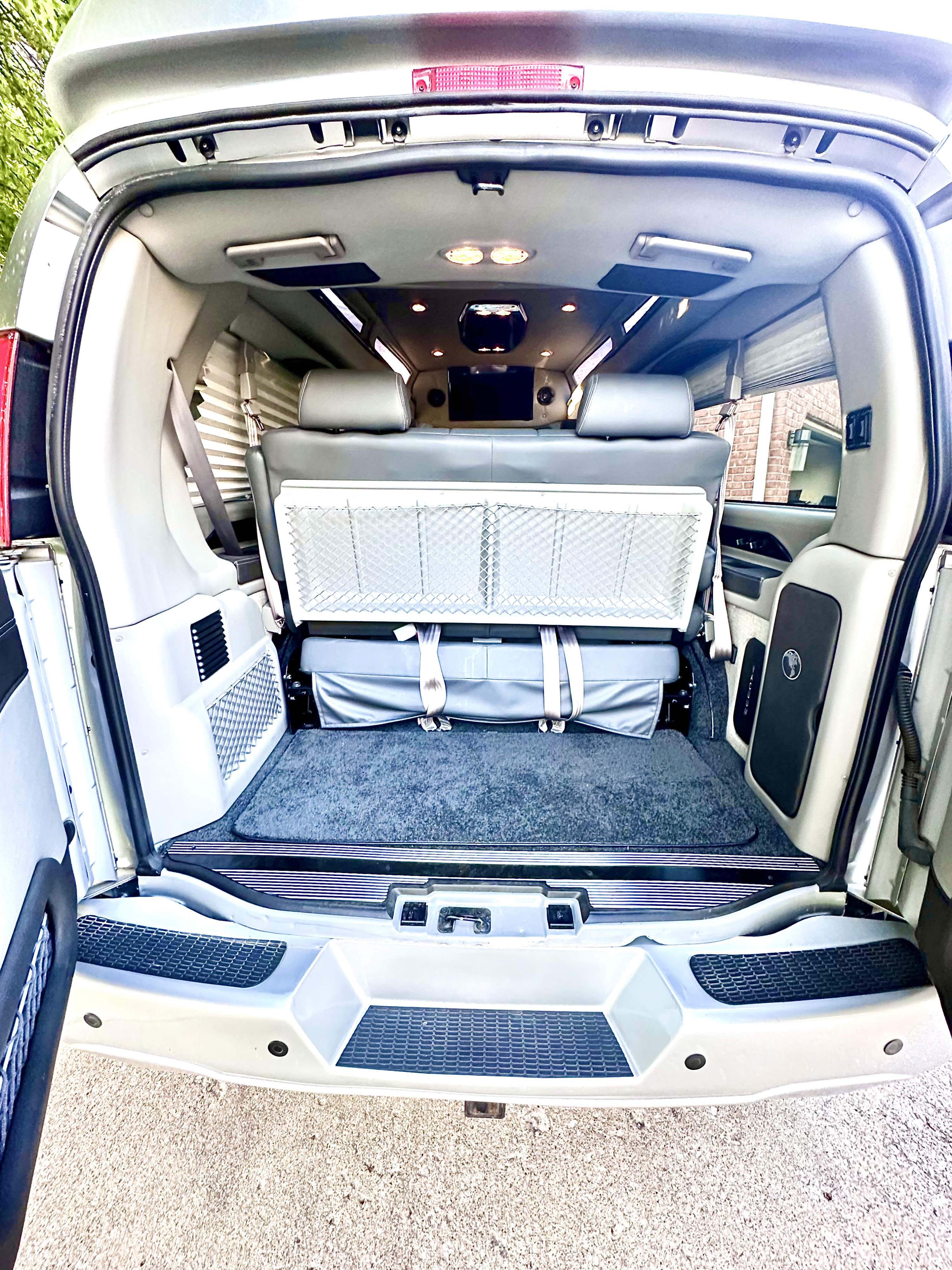 Spacious RV rental rear interior: folded bench seat with mesh storage, carpeted floor, and bright overhead lights.. CHEVROLET Cargo Van 2020