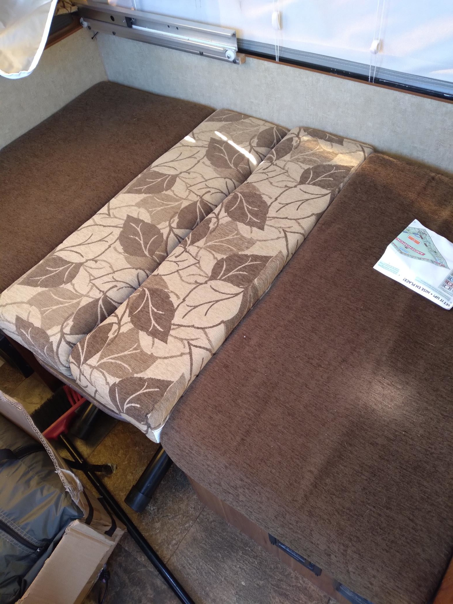 RV rental interior: convertible dinette bed with patterned brown cushions and a bench seat. Floor storage below.. Starcraft Starflyer 2015