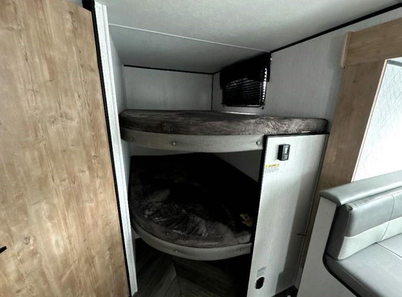 Inside this RV rental, find cozy bunk beds for sleeping, with a window and blinds above, and a partial dinette visible.. Heartland RVs Prowler Lynx 2023