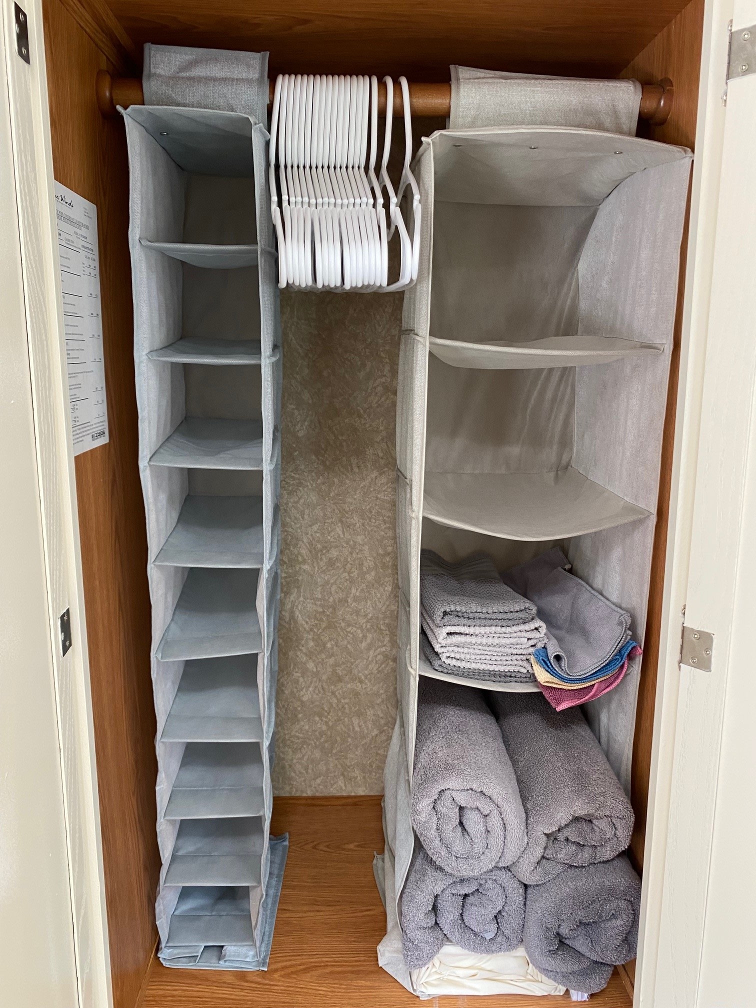 RV rental closet: compact, organized storage featuring grey hanging fabric shelves, white hangers, and neatly folded towels.. Four Winds 5000 2008