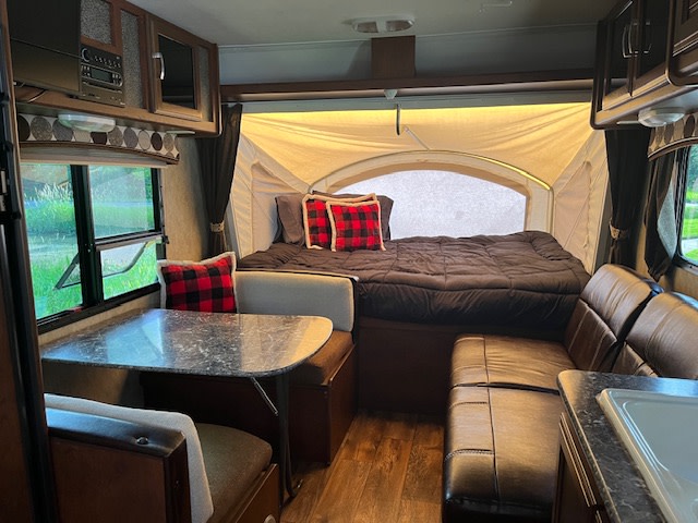 Spacious rv rental interior featuring a comfy bed in a pop-out, dinette, and living area. Ready for your adventure.. Keystone RV Passport Ultra Lite 2015