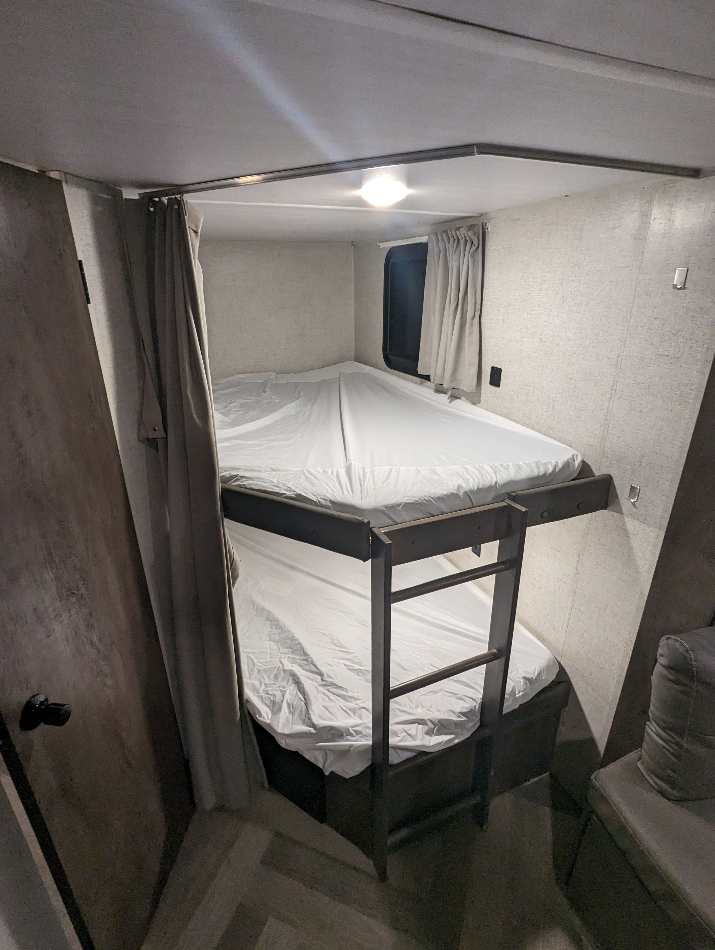 Comfortable bunk beds in an RV rental, featuring a window, privacy curtain, and ladder for easy access.. Forest River Salem Cruise Lite 2020