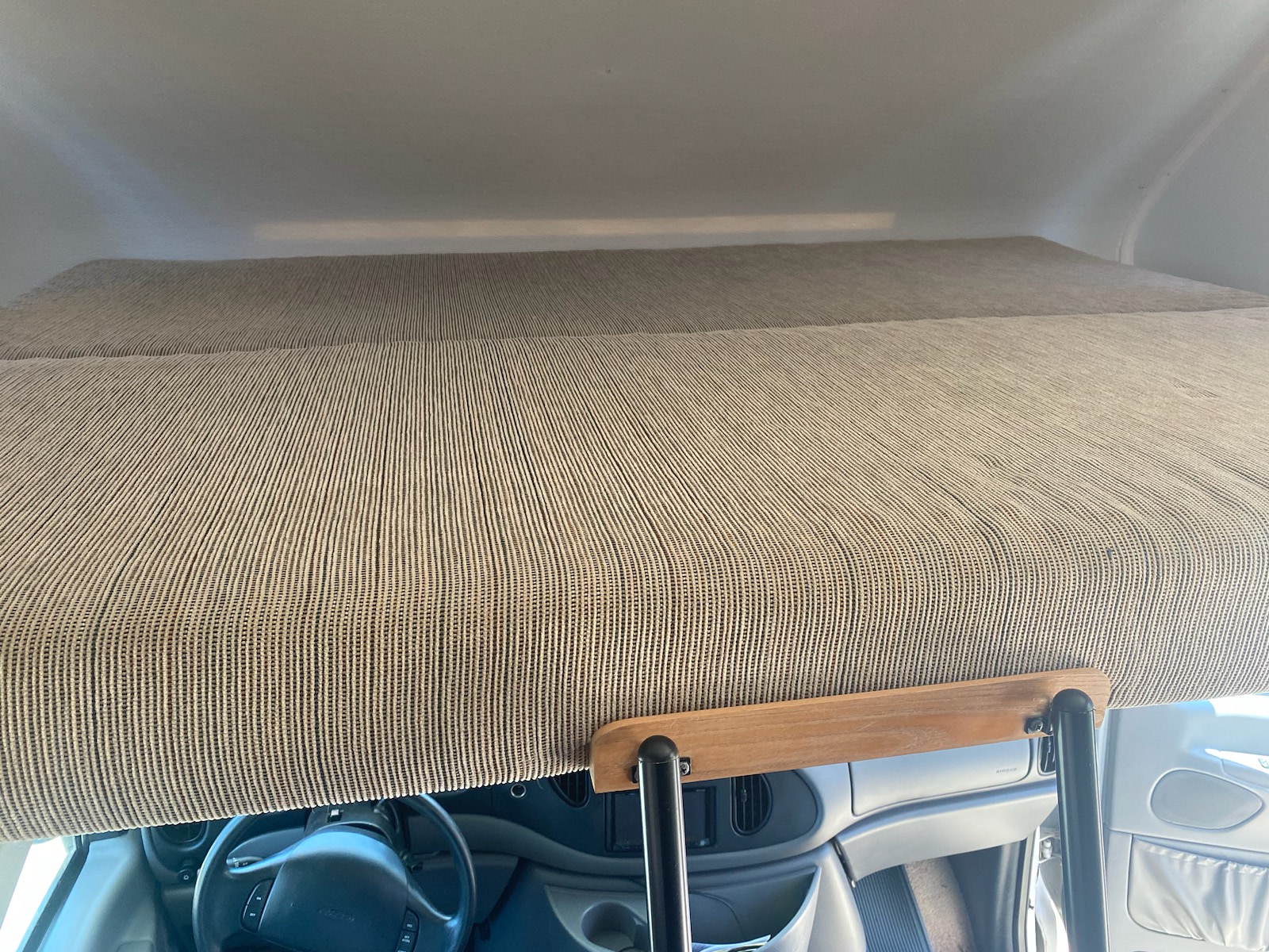 View of the overhead bunk in an RV rental, featuring a mattress and support railing above the driver's cab.. Winnebago Minnie Winnie 1998