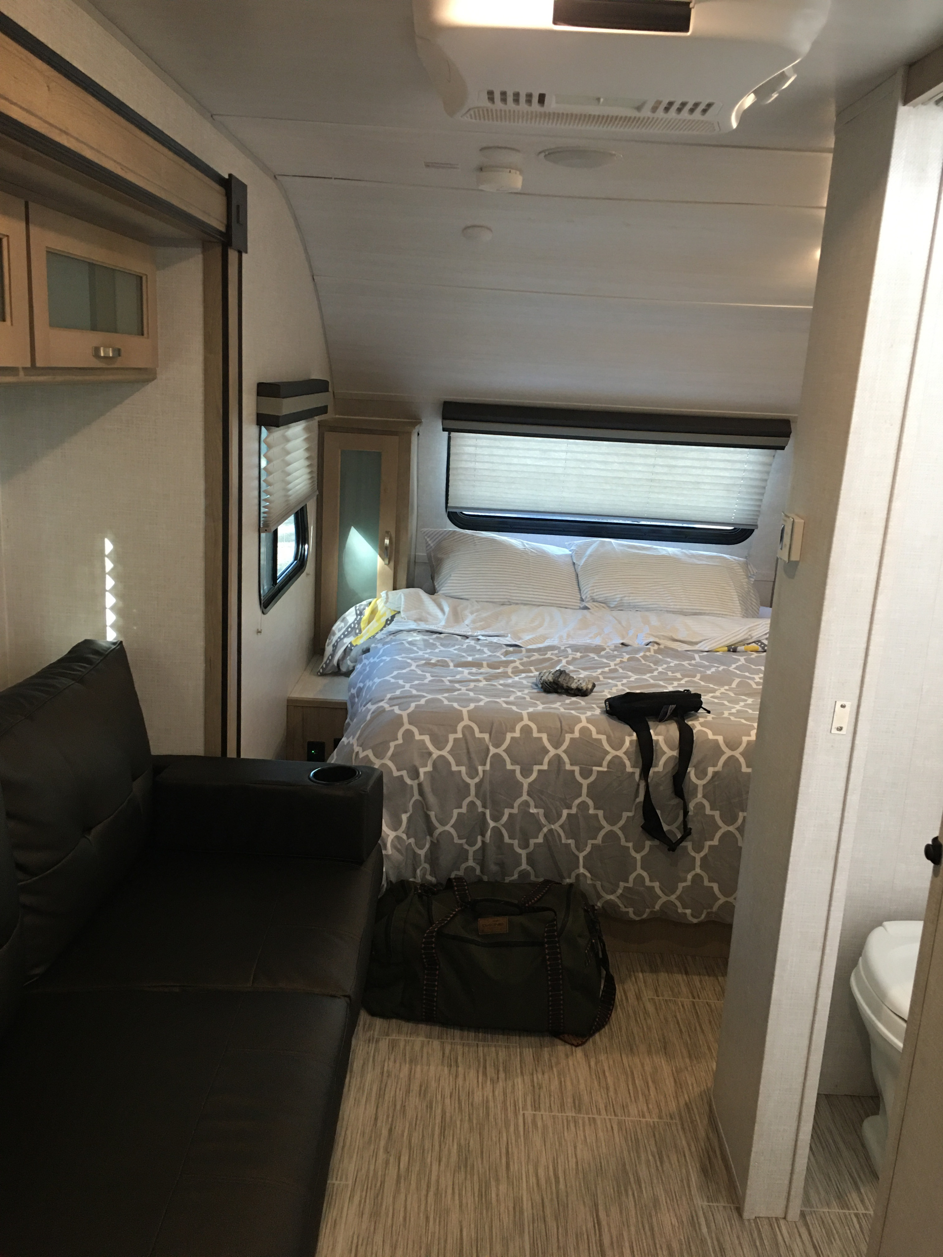 Inside an RV rental: a compact living space with a dark sofa, leading to a comfortable bedroom area.. Forest River R-Pod 196 2020
