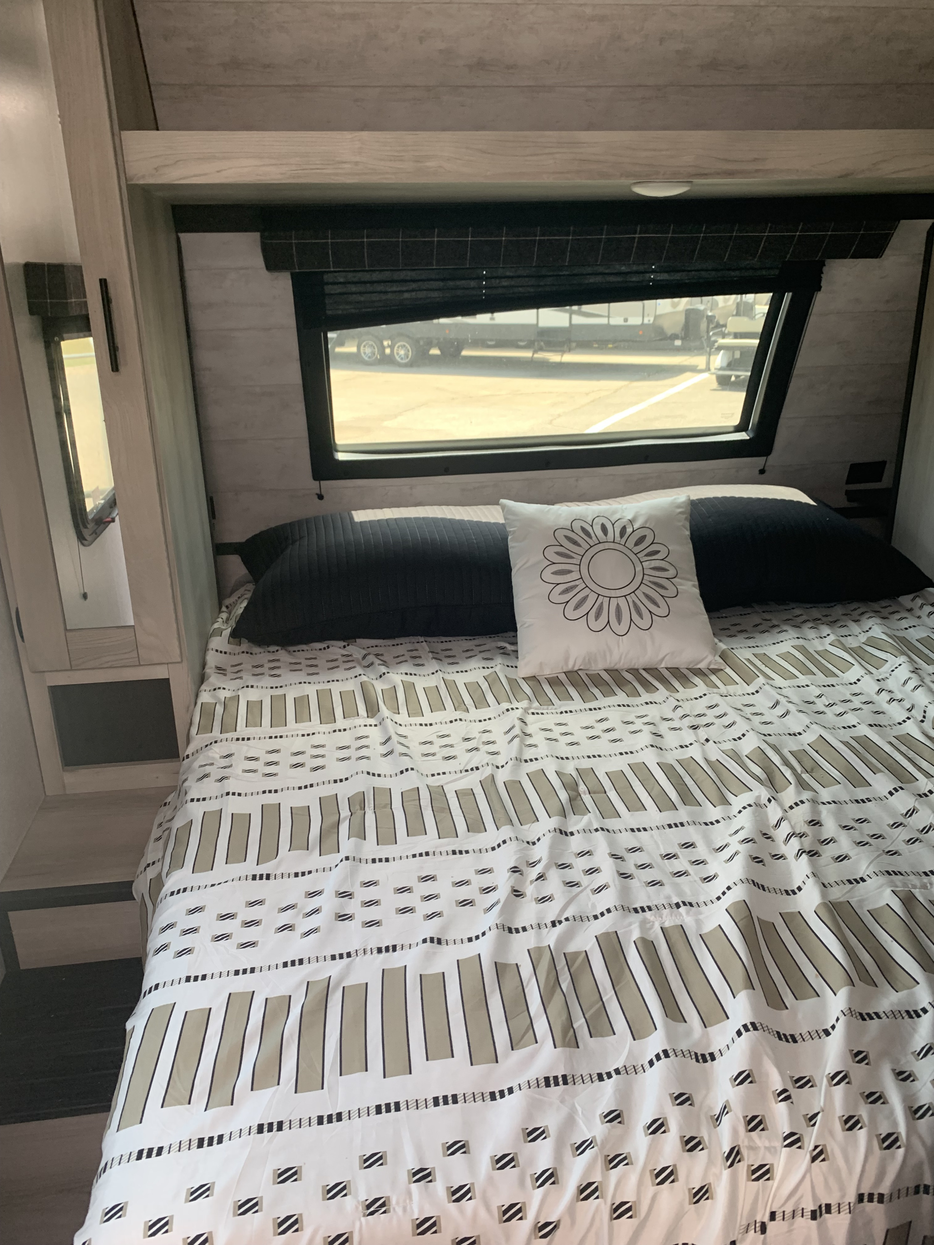 RV rental bedroom with a bed, patterned cover, black and floral pillows, and a window offering outdoor views.. Connect C322BHK 2022