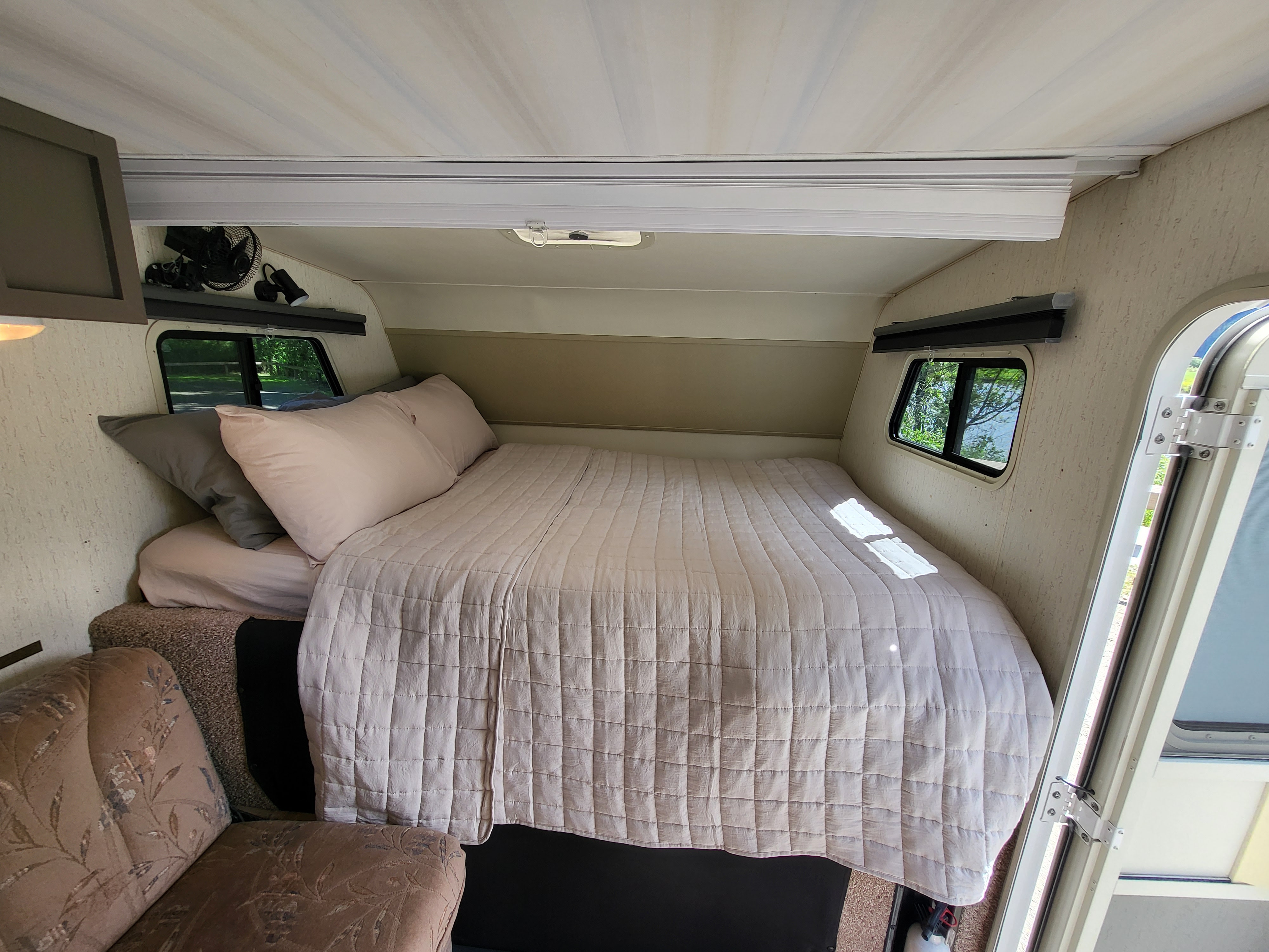 RV rental: Cozy bedroom interior with a large bed, pillows, and windows offering outdoor views.. Winnebago Warrior 1992
