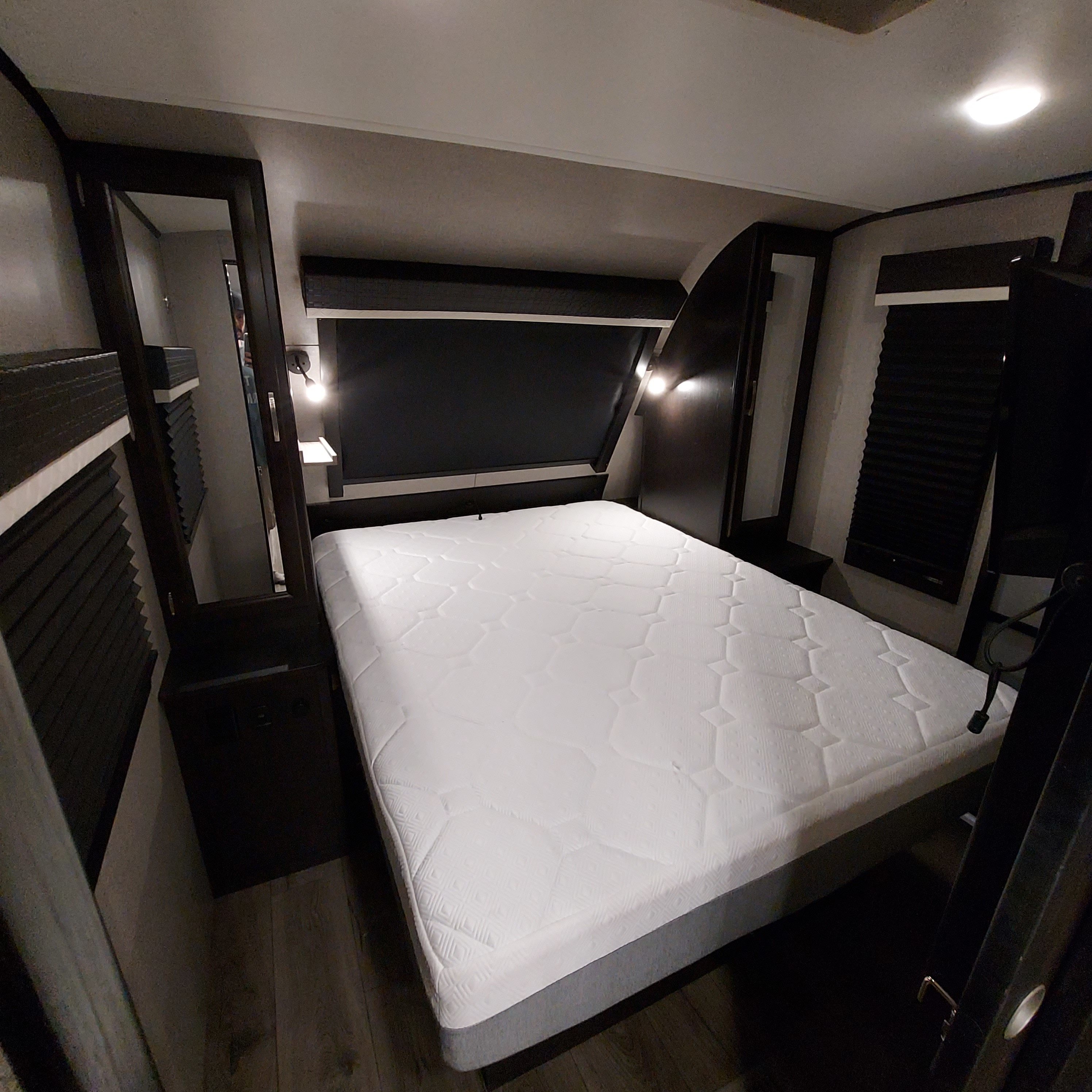 Cozy RV rental bedroom featuring a spacious bed, bedside lighting, and built-in storage, perfect for travel.. Jayco White Hawk 2021