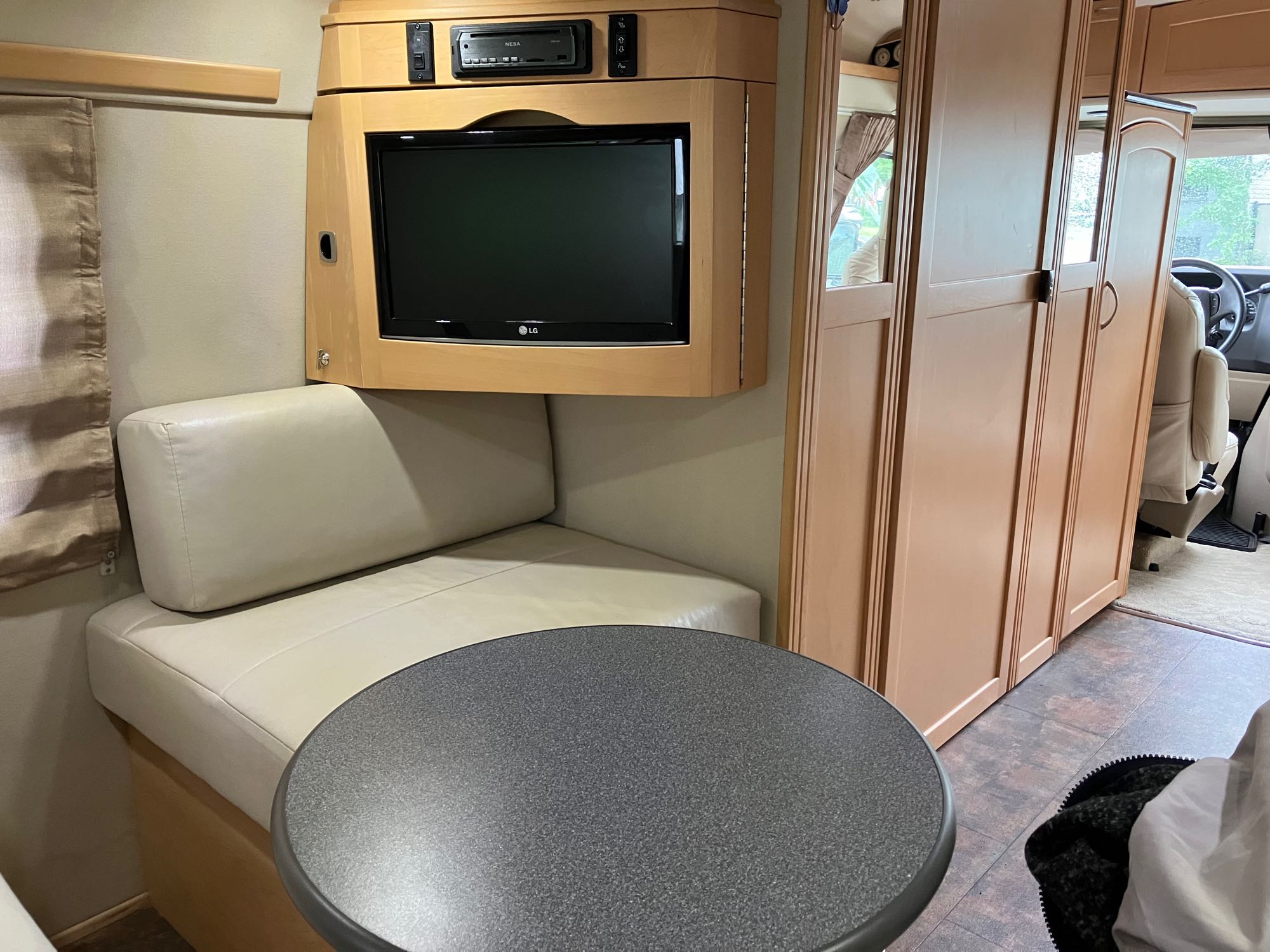 Experience comfort in this RV rental's cozy dinette, complete with an LG TV entertainment system and ample cabinetry.. Pleasure-Way Pleasure-Way Class B 2011