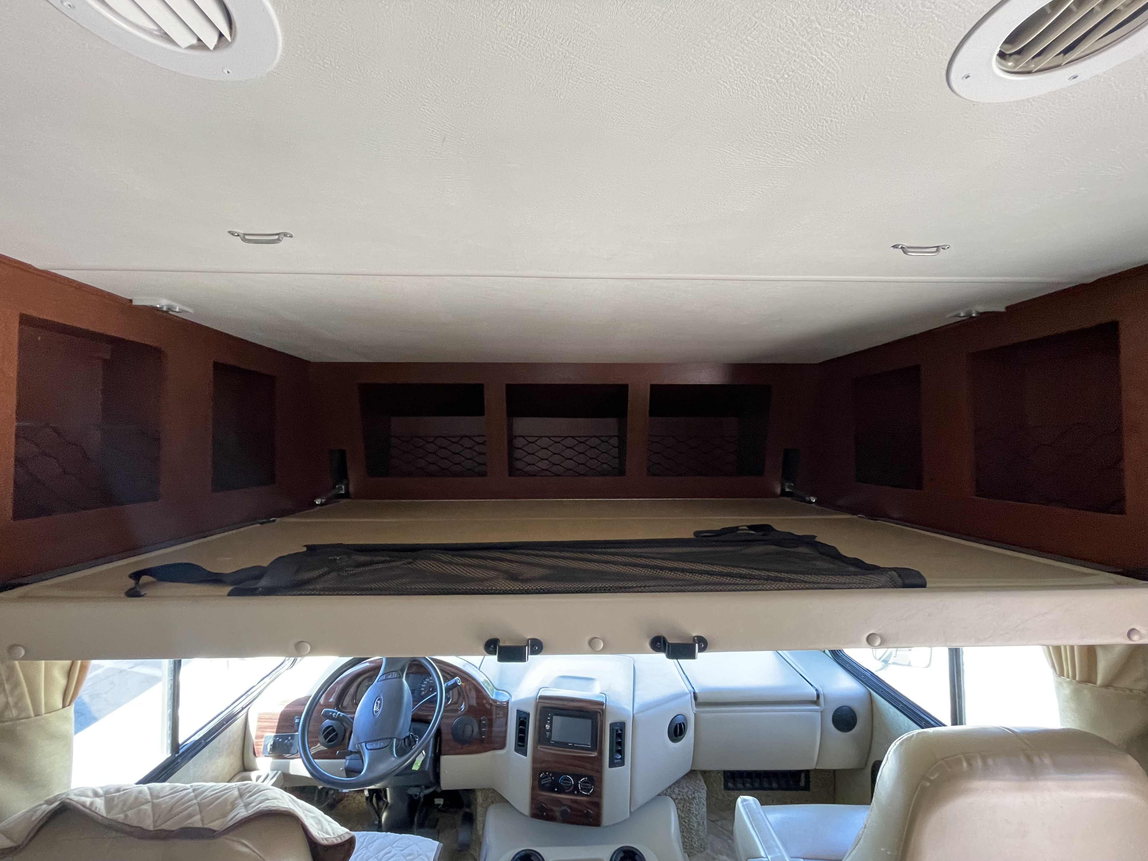 Inside an RV rental: view from the living area towards the cockpit, showcasing the overhead bunk, dashboard, and storage.. Thor Motor Coach A.C.E 2017