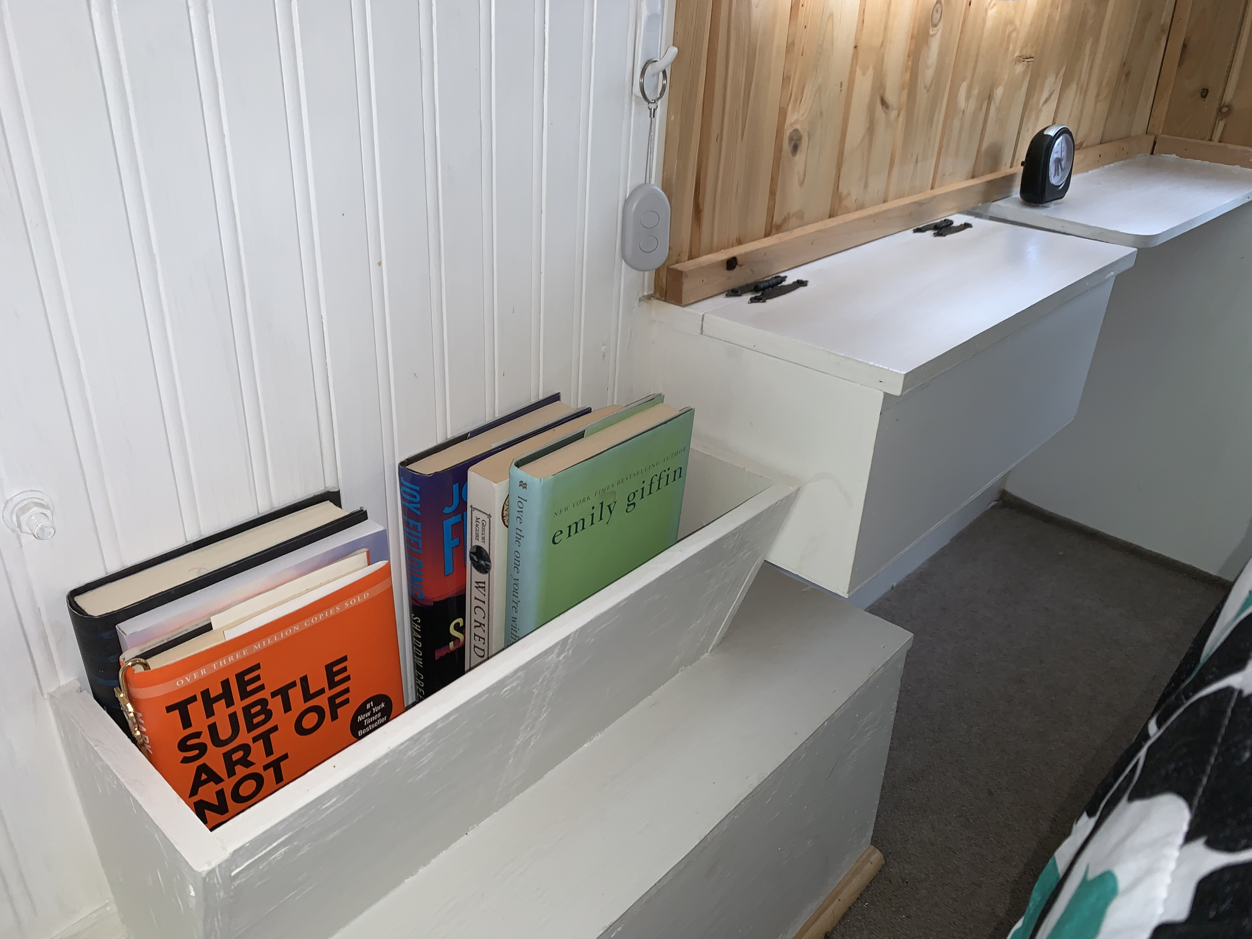 RV rental interior featuring a cozy built-in bed with storage shelves, books, and a clock, designed for efficiency.. Serro Scotty Sportsman 1984