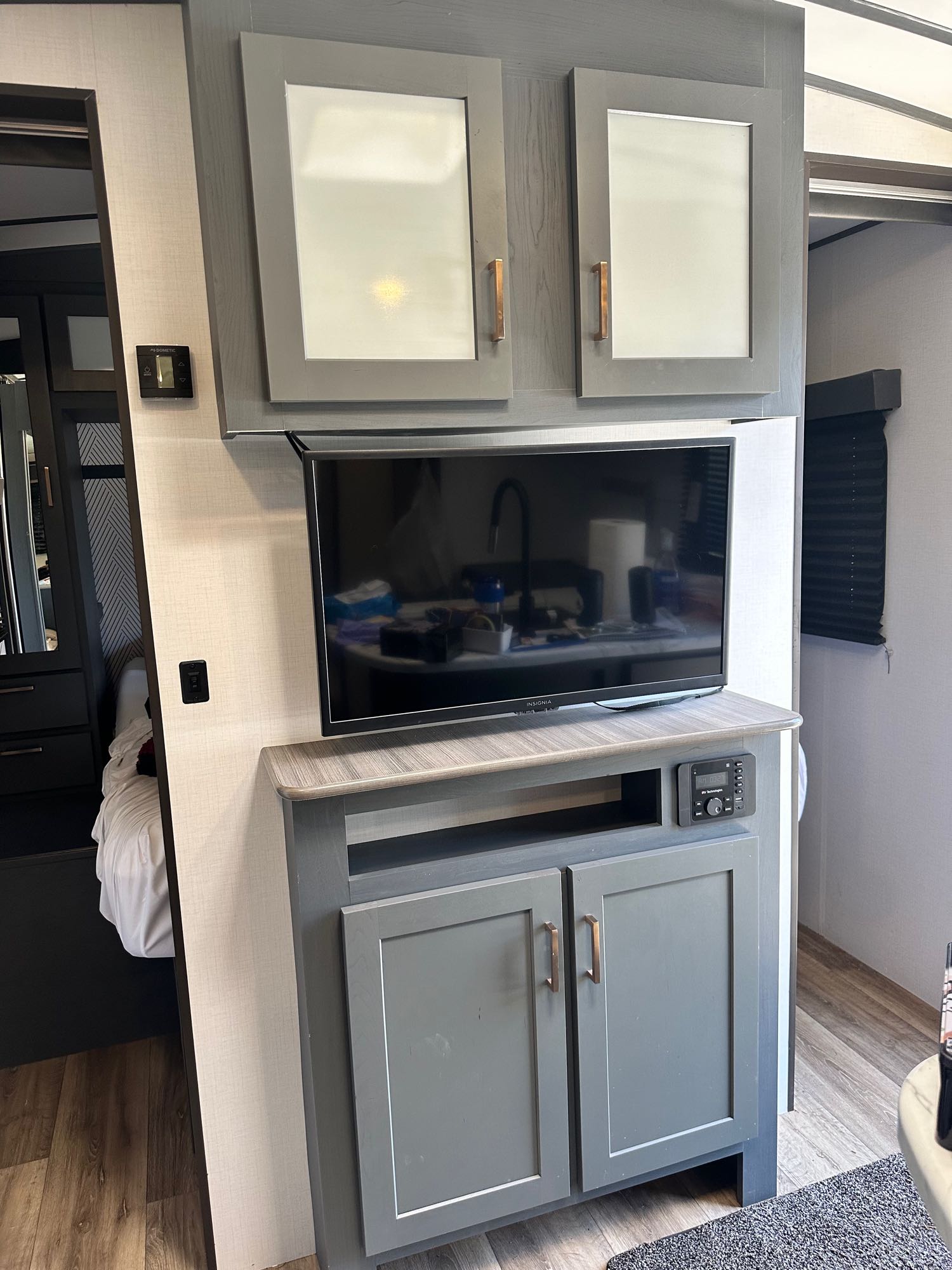 Stylish RV rental living space featuring a gray TV unit, overhead cabinets, and bedroom access.. Keystone RV Bullet Ultra Lite 2022