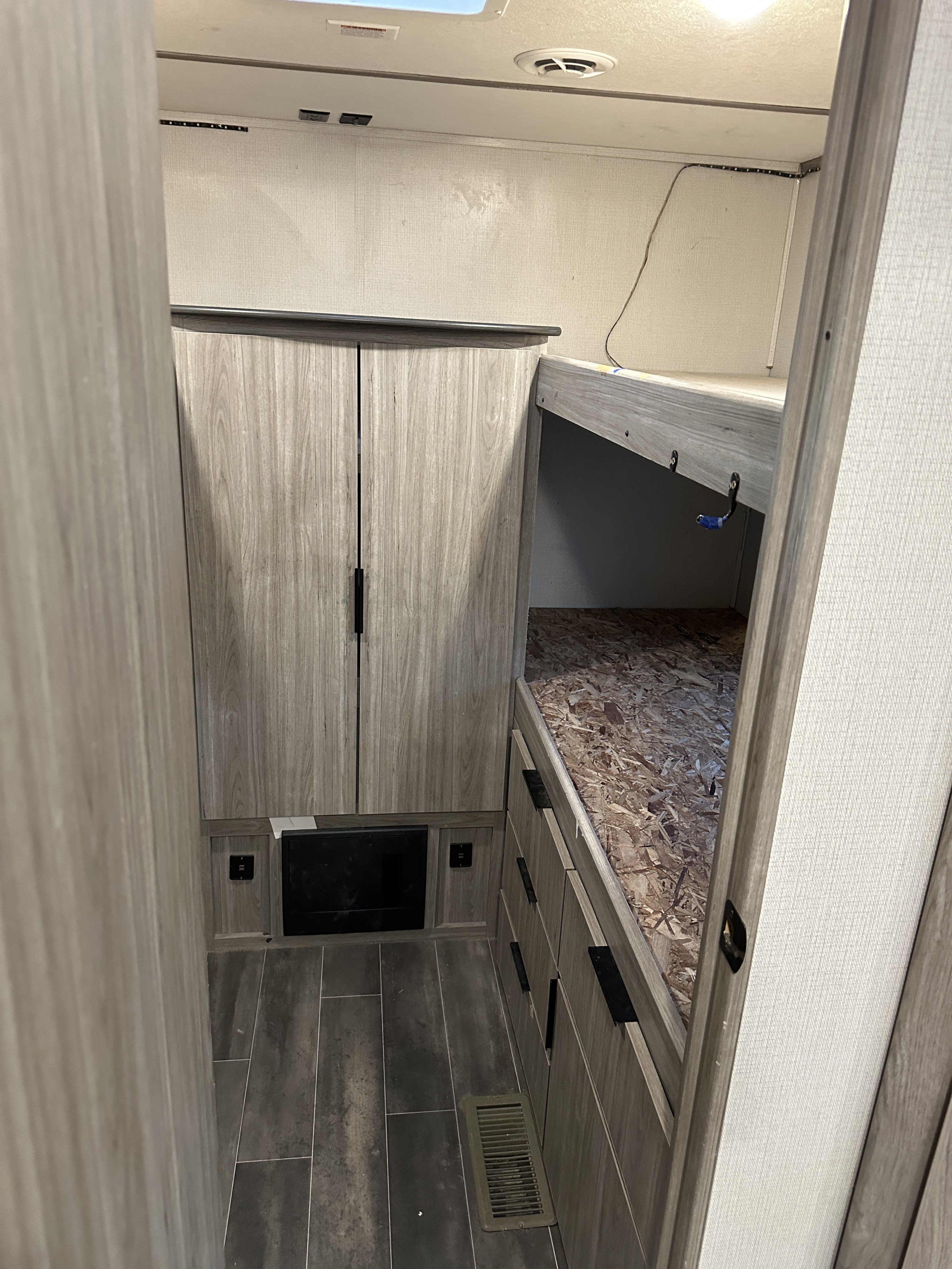 RV rental interior: A hallway view shows modern wood-look bunk beds, a large wardrobe, and durable plank flooring.. Keystone RV Passport SL 2021