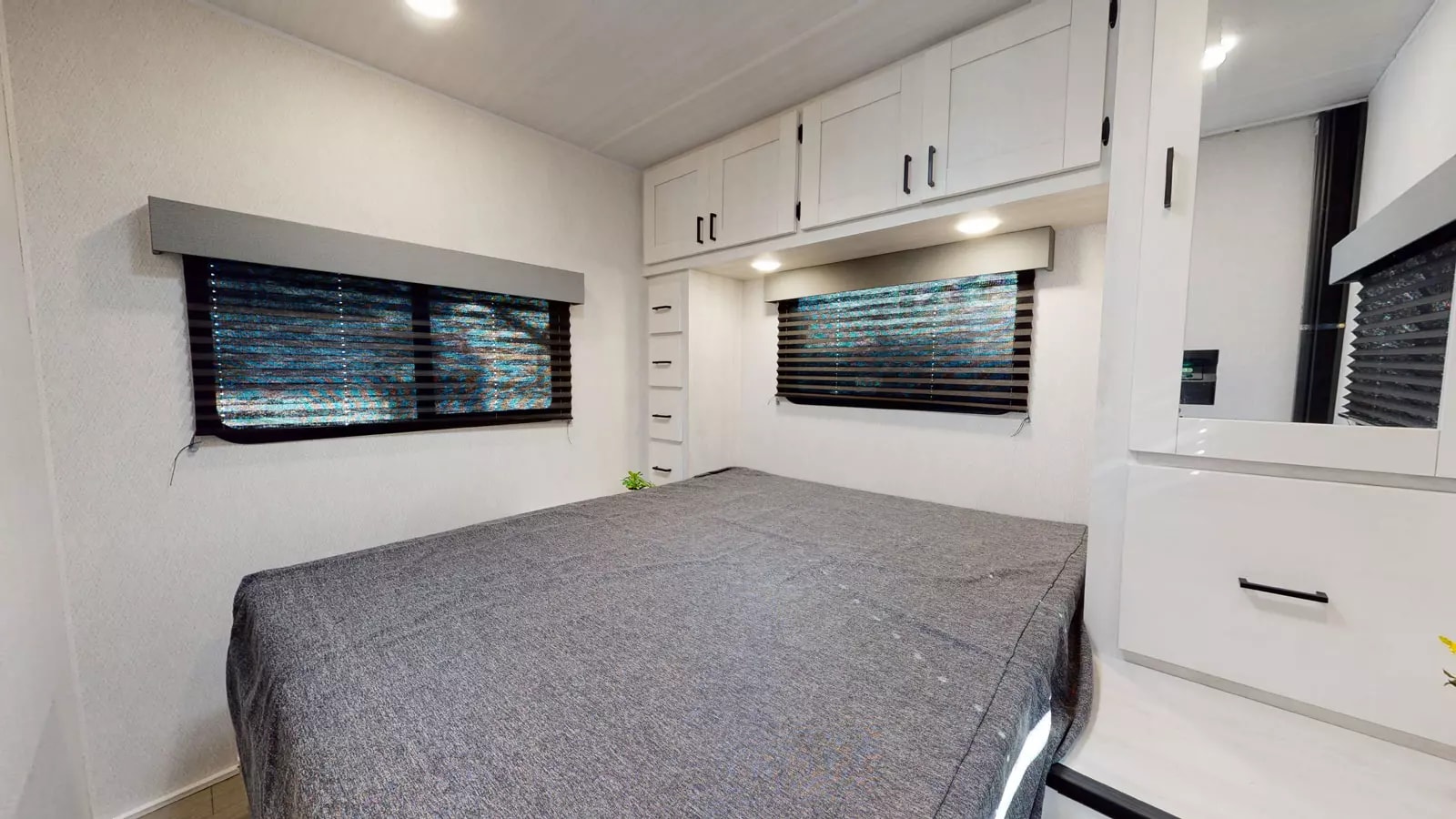 Explore this cozy RV rental bedroom featuring a bed, overhead storage, windows, and bright white interior.. East to West Entrada 2700NS 2025