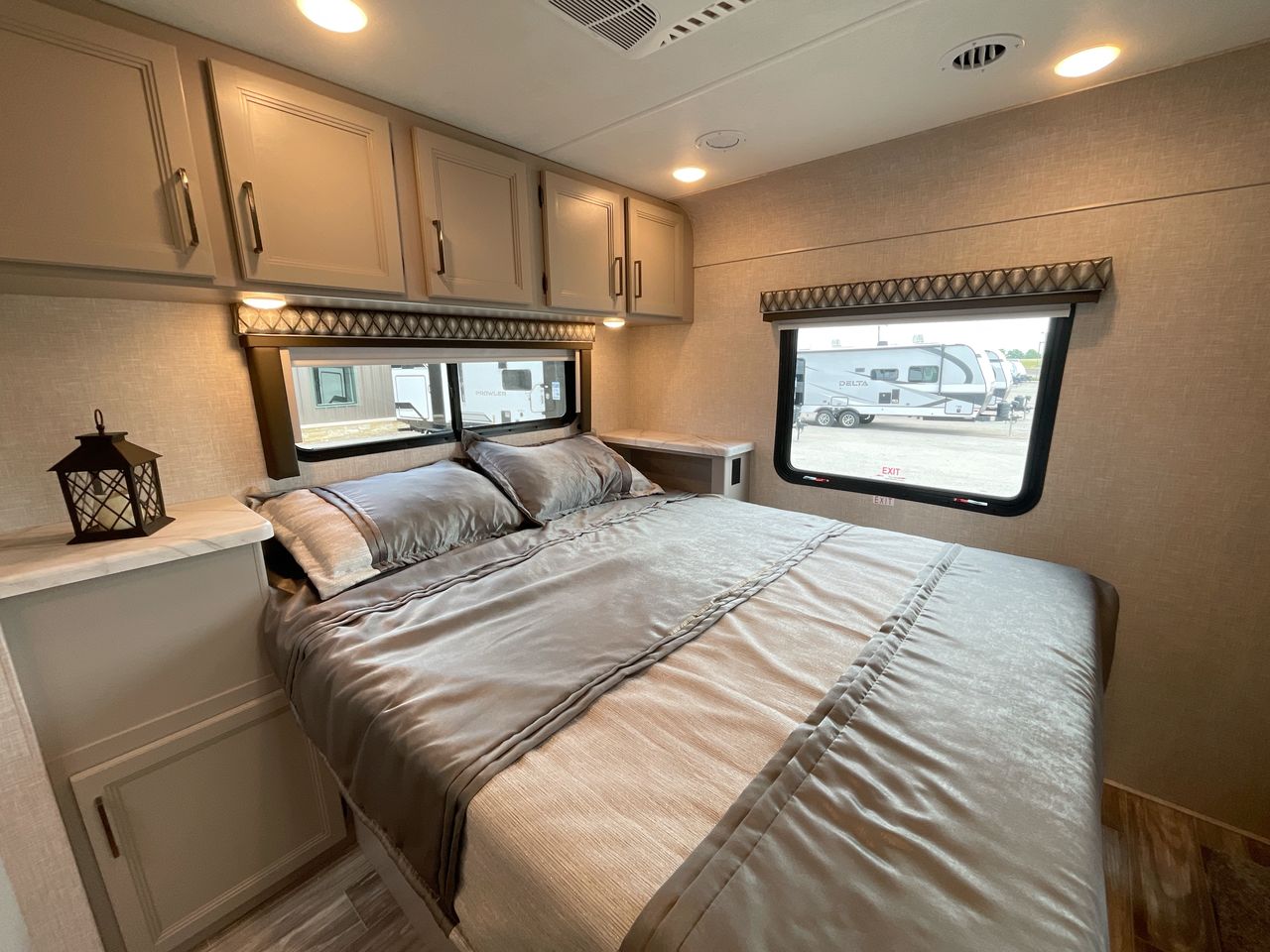 Comfortable RV rental bedroom with a large bed, overhead cabinets, and window view of other RVs.. Thor Motor Coach Other 2024