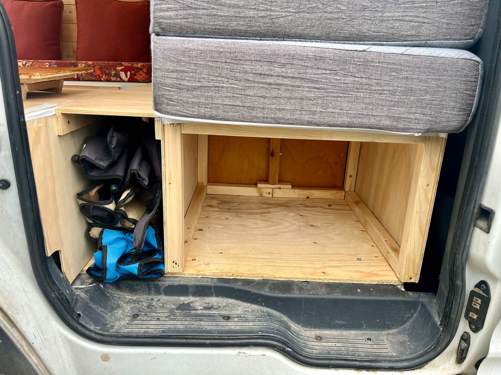 RV rental van interior featuring custom wood storage under a bed/bench cushion, perfect for organized gear.. ford transit Connect 2011