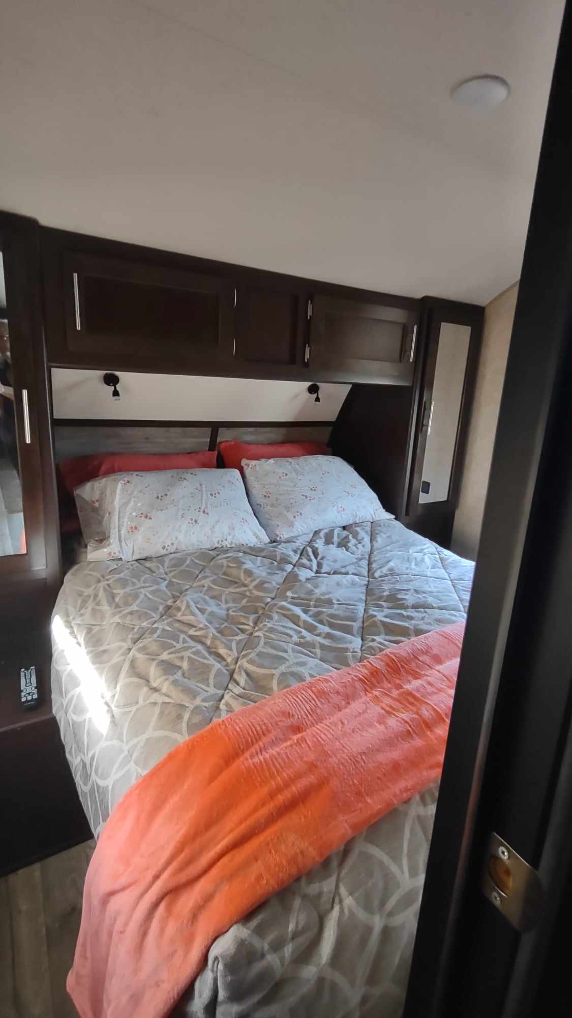 RV rental bedroom with a cozy bed, patterned comforter, overhead storage cabinets, and side mirrors. Ideal for travel.. Forest River Cherokee 2017