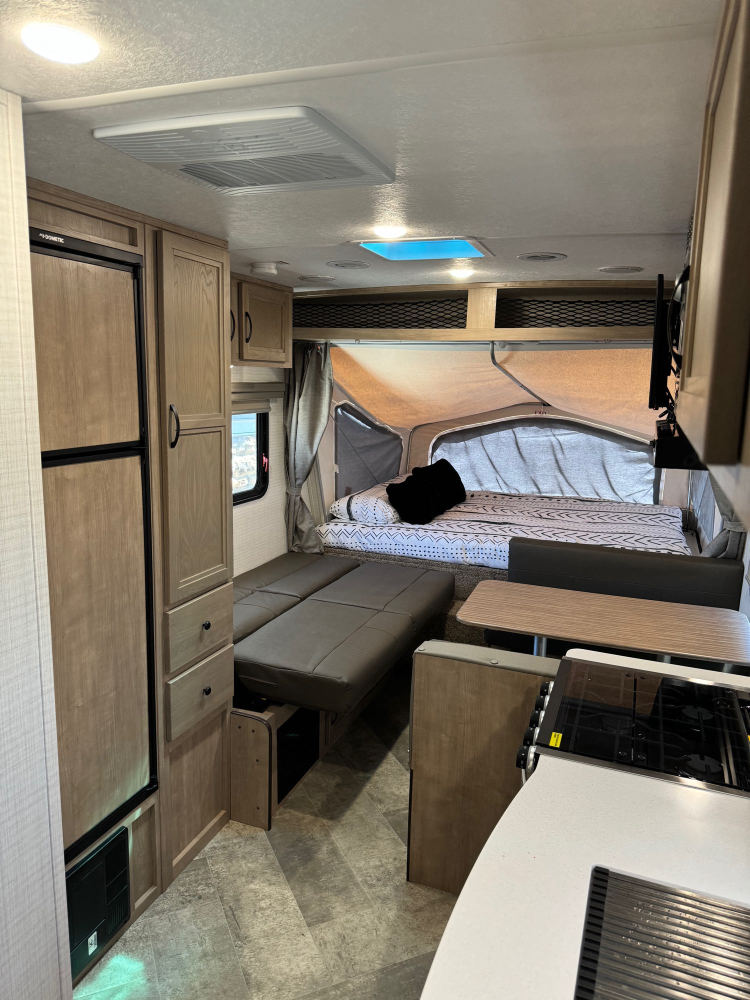 Step inside this RV rental: pop-out bed, convertible dinette, kitchen, fridge, light wood cabinets, and AC unit.. Forest River Palomino Solaire 2023
